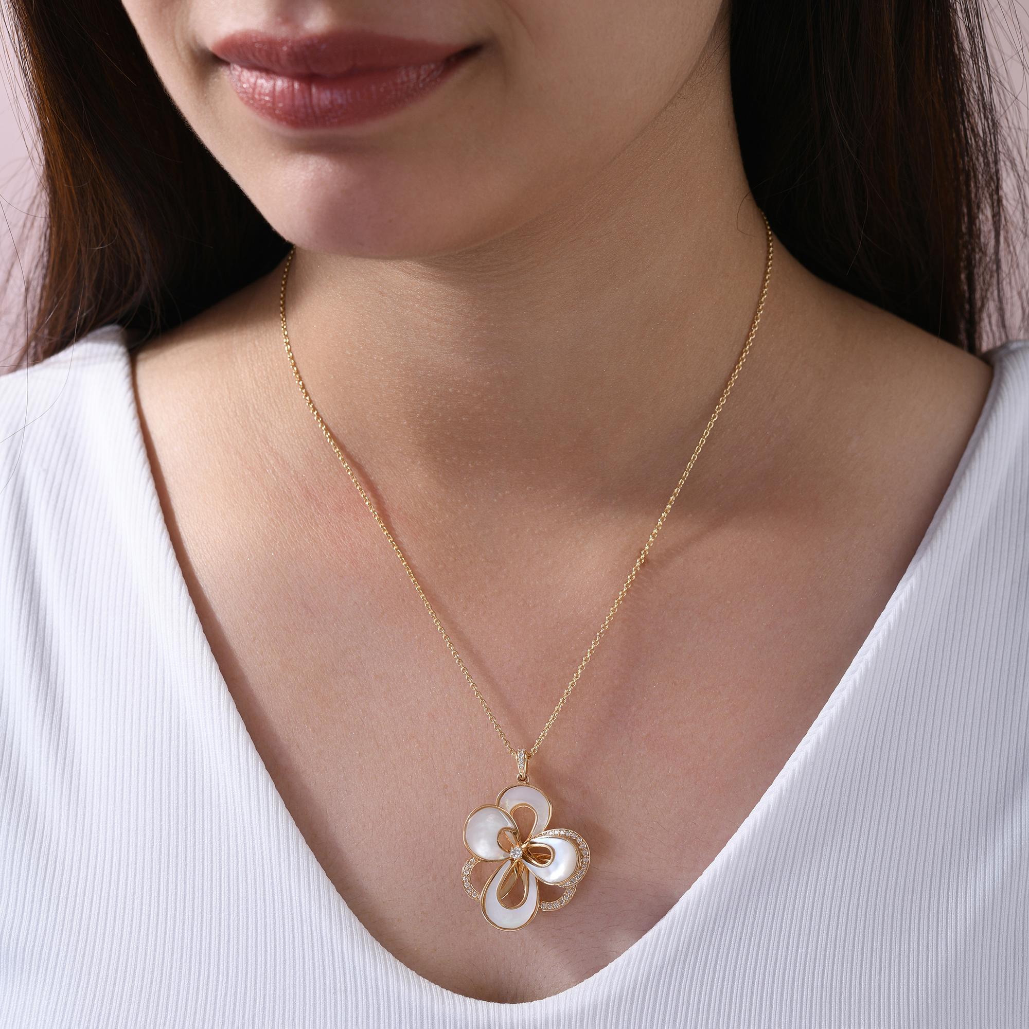 Questa collana con ciondolo in oro giallo 18 carati con diamanti e madreperla naturale è caratterizzata da petali intarsiati di madreperla bianca e file di piccoli diamanti naturali che formano un ciondolo a forma di fiore organico. 
I diamanti sono
