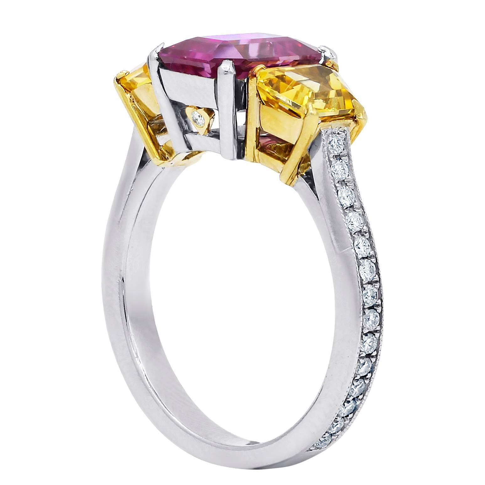 Platinum and 18 karat yellow gold three stone ring containing emerald cut pink sapphire in the center,weighing 2.45 carats set with 1.79 cts trapezoid yellow sapphires on each side and accented by 0.80 cts round cut diamonds .
