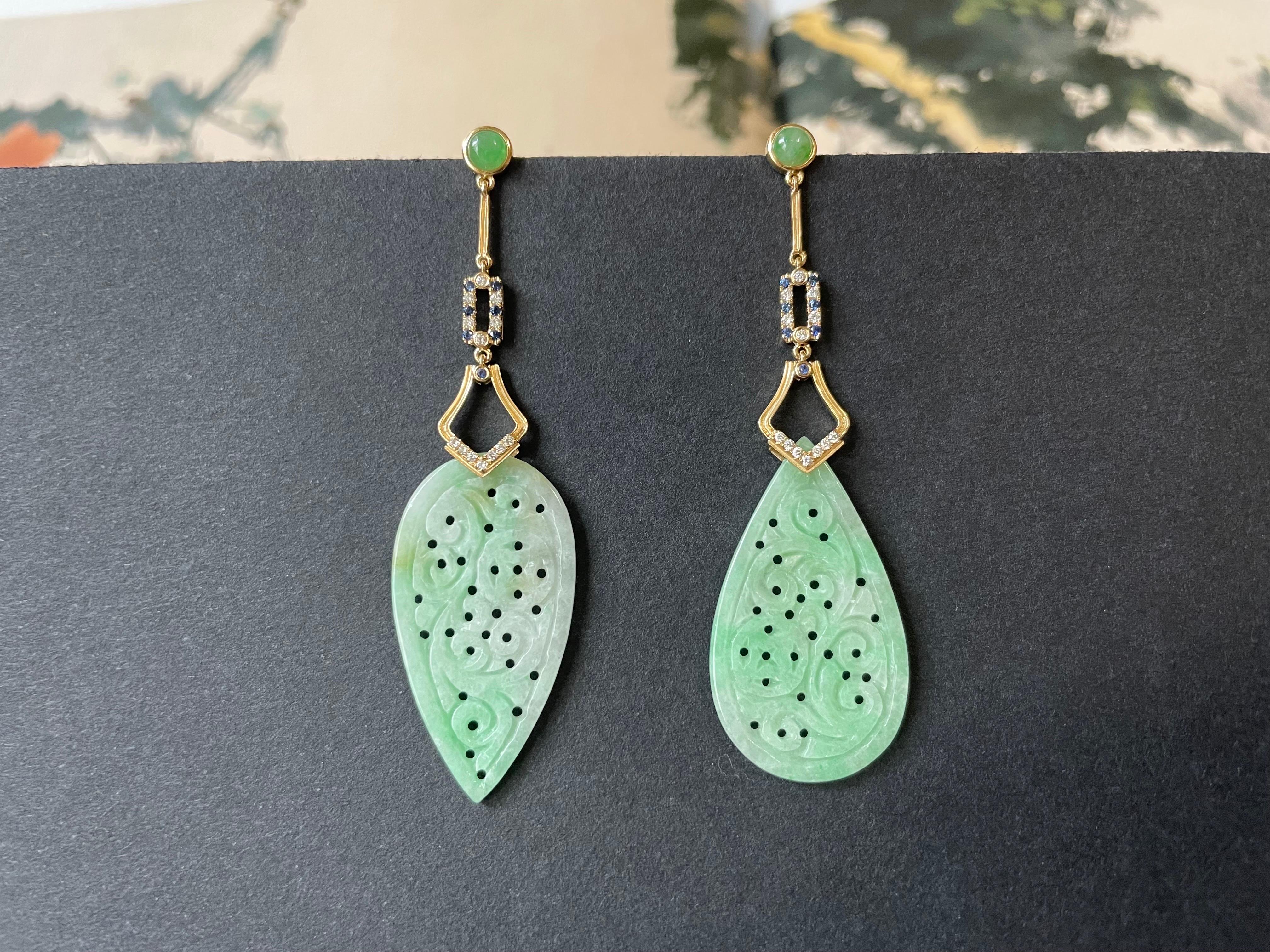 The custom-designed and handcrafted earrings are set with Myanmar apple green jadeite in an ancient carved drop shape pattern. These luxurious jadeite ear studs are framed in 18k gold embellished with vibrant blue sapphires, high-quality diamonds,