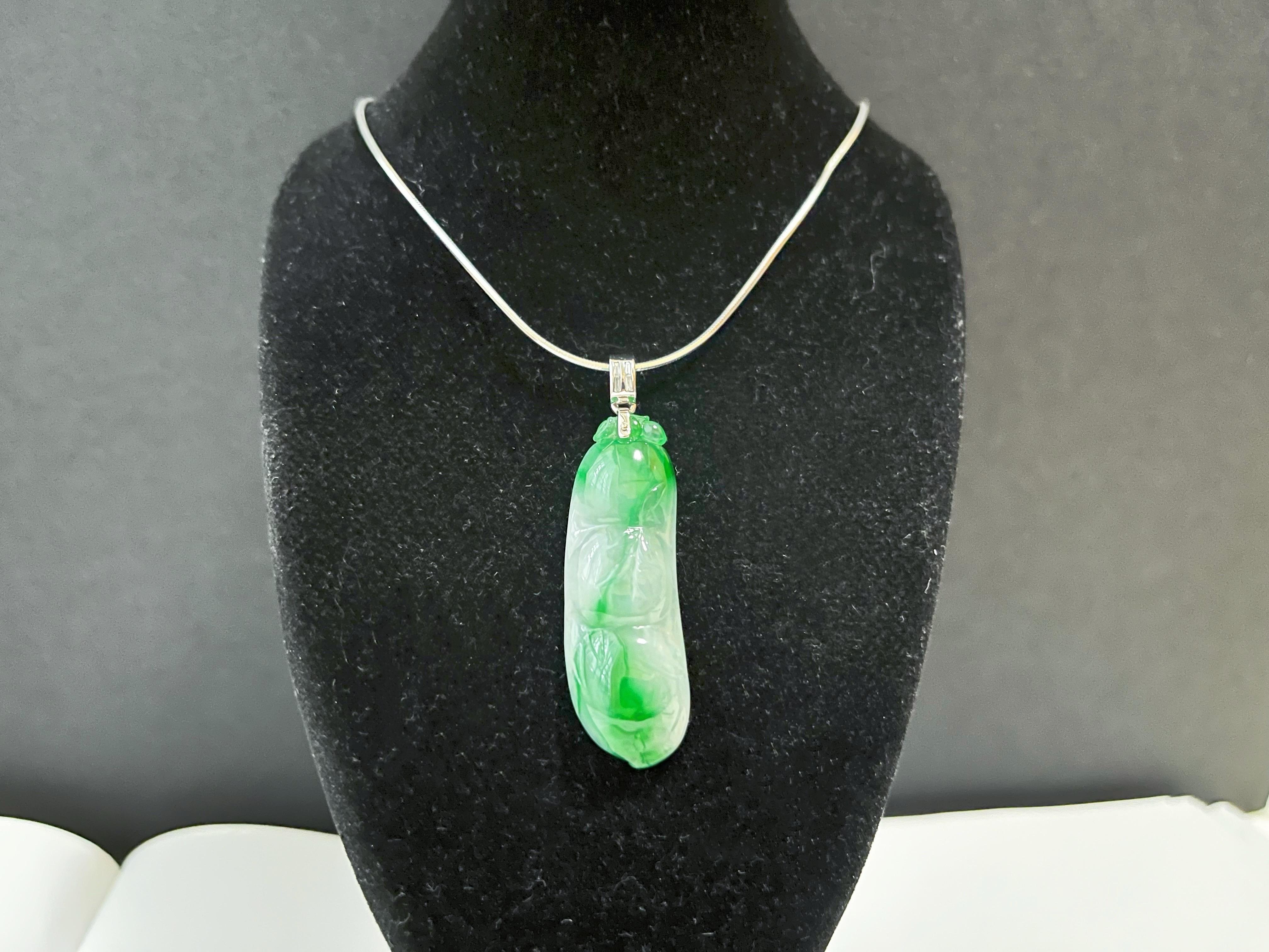 This jade pendant is 100% natural, untreated, and undyed Type-A Myanmar jadeite jade. It is hand-carved into a pea pod. There are three peas in a pod carved to look like a green bean, symbolizing luck, prosperity, and longevity. Beautiful vivid