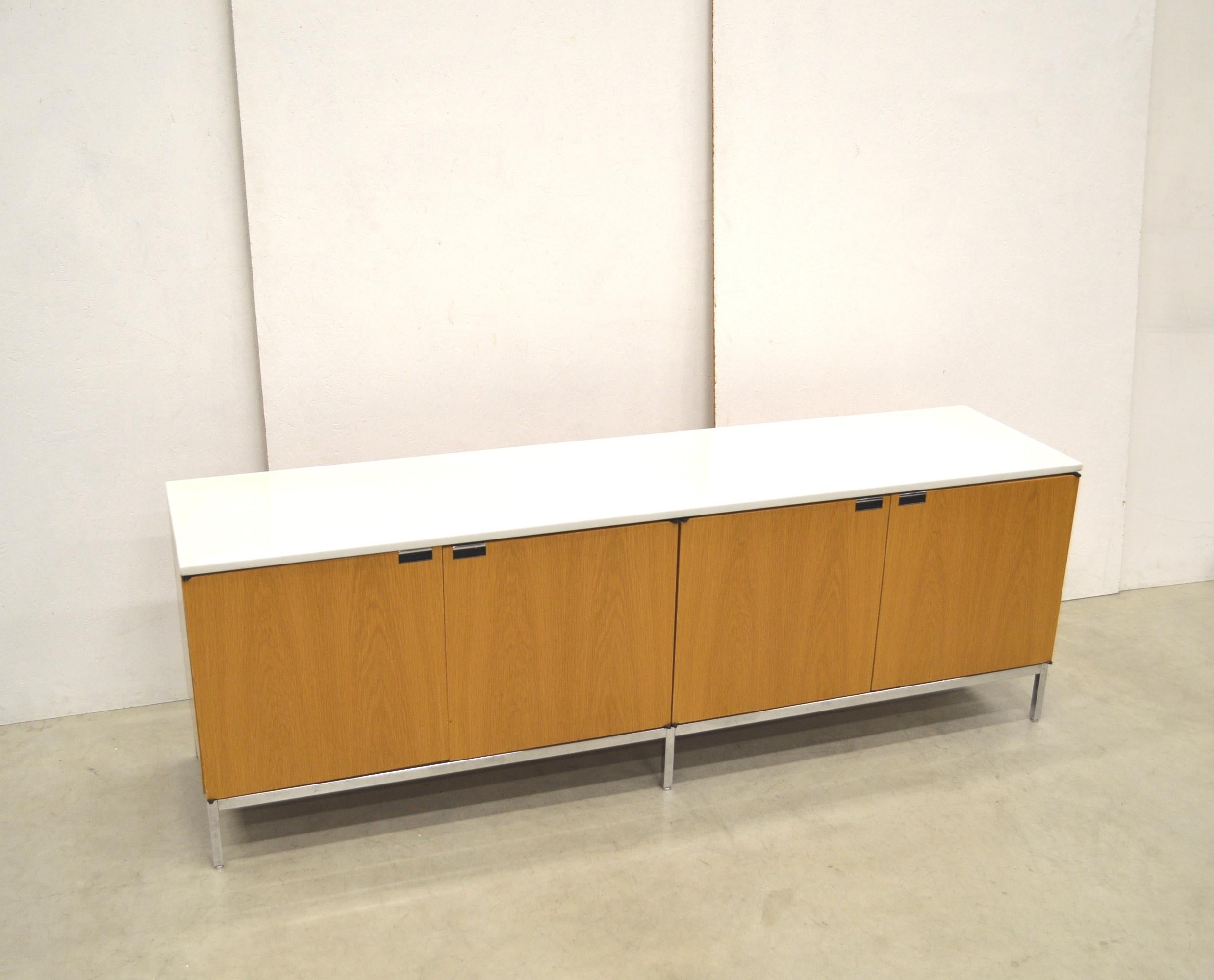 This sideboard in natural oak with marble top by Florence Knoll was produced by Knoll International in the 90s. 
It features the original signature at the feet.

The impressive piece features 4 doors on a very nice chromed steel base. It features