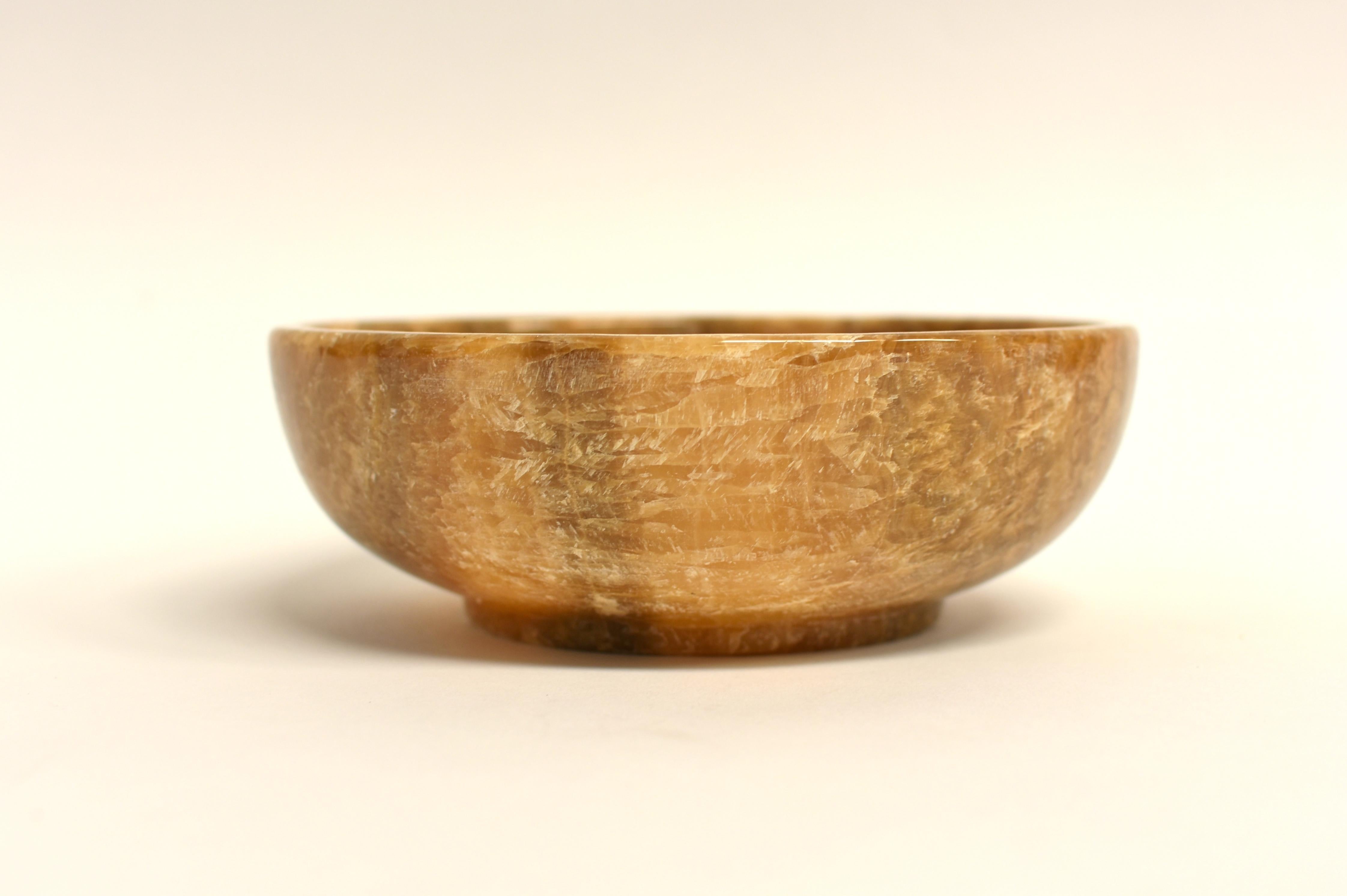 This amazing round bowl is a testament to the beauty of natural stone. Crafted from solid finest-grade onyx, it showcases a captivating interplay of cream, caramel and russet hues. The intricate veining within the stone adds a unique character to