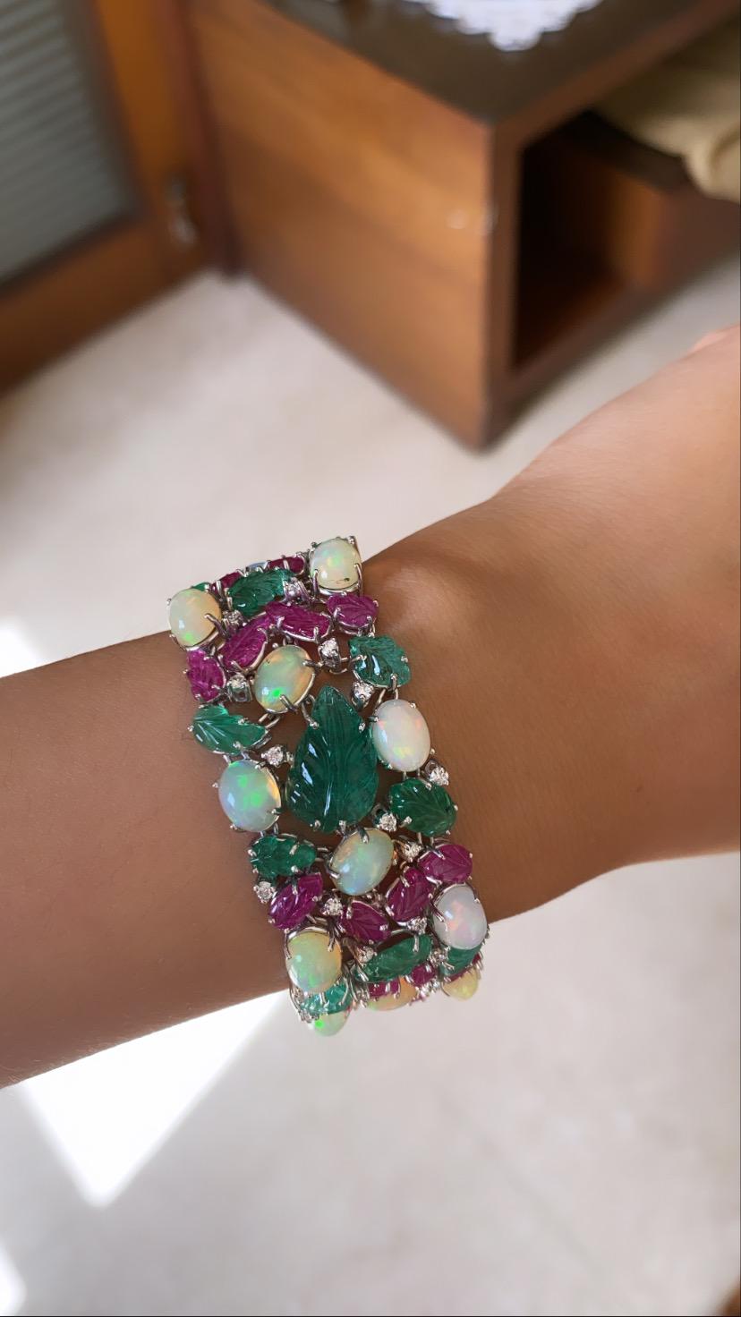 A beautiful and modern multi color bracelet set in 18k white gold with carved natural emerald, ruby and opal cabochon with diamonds. The colorstone are natural with opal weight 27.70 carats , emerald and ruby combined weight of 35.47 carats and