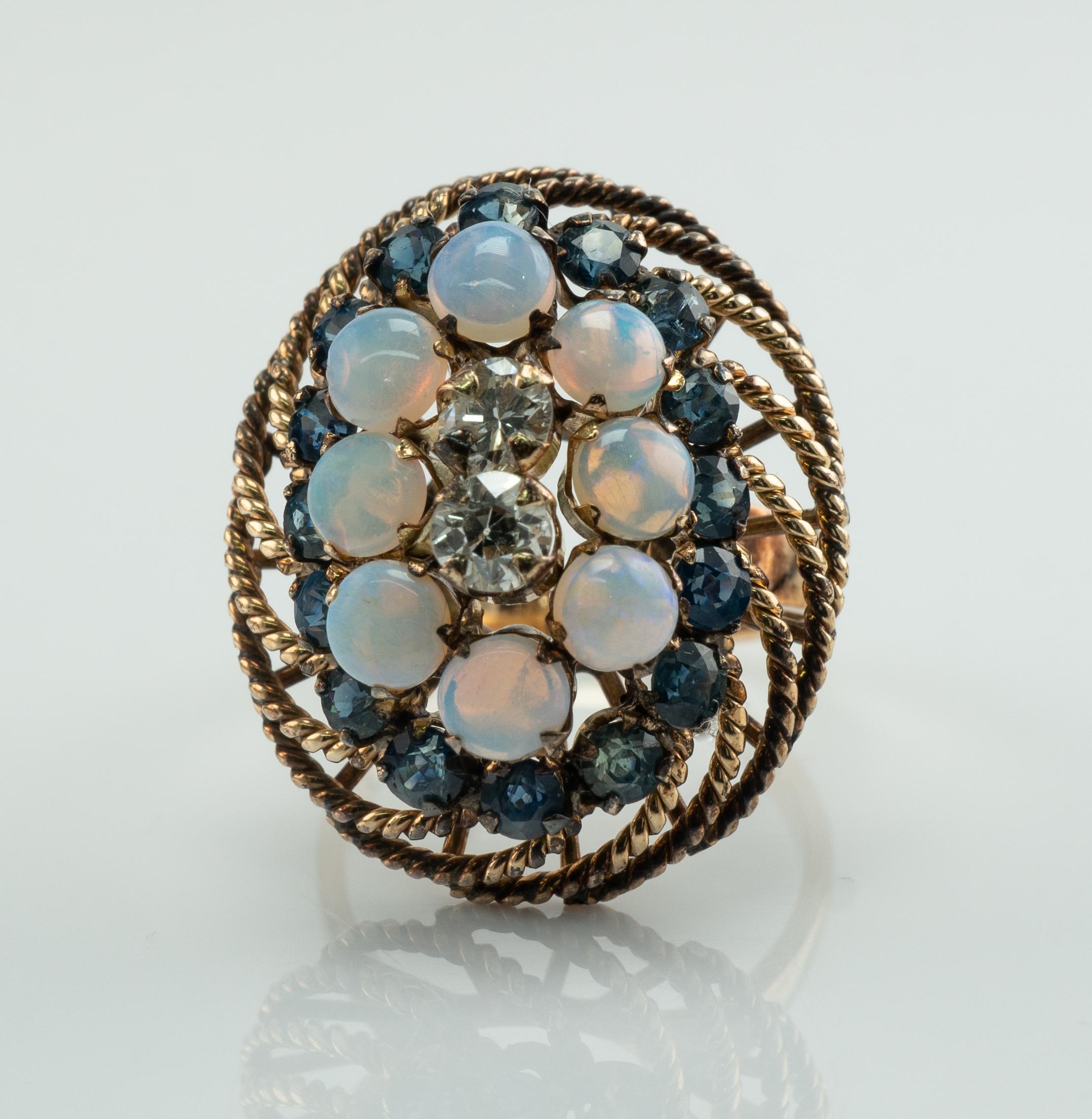 This beautiful large vintage ring is finely crafted in solid 14K Yellow gold and set with genuine Earth mined Opals, Sapphires, and Diamonds. 
Circa 1950s.
There are two diamonds in the center. 
One diamond is an Old mine gem = .18 carat of  VS1