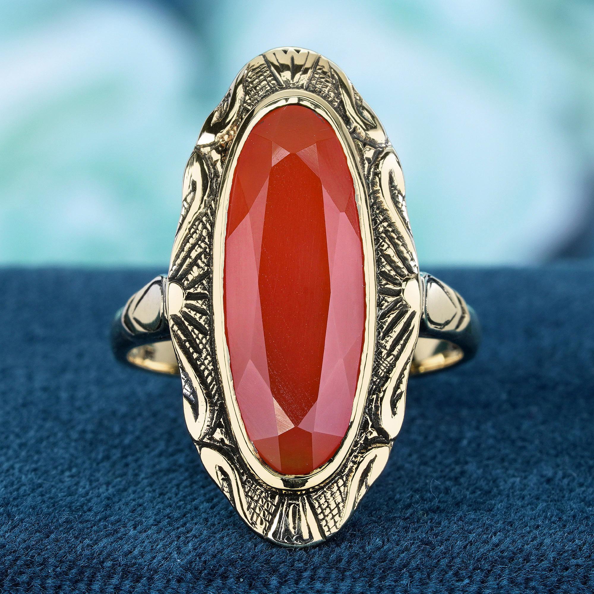 This vintage-inspired ring’s centerpiece is an oval cut natural carnelian, known for its vivid orange hue. This outstanding carnelian is set amidst a backdrop of yellow gold, which is adorned with intricate vintage-style patterns, enhancing the