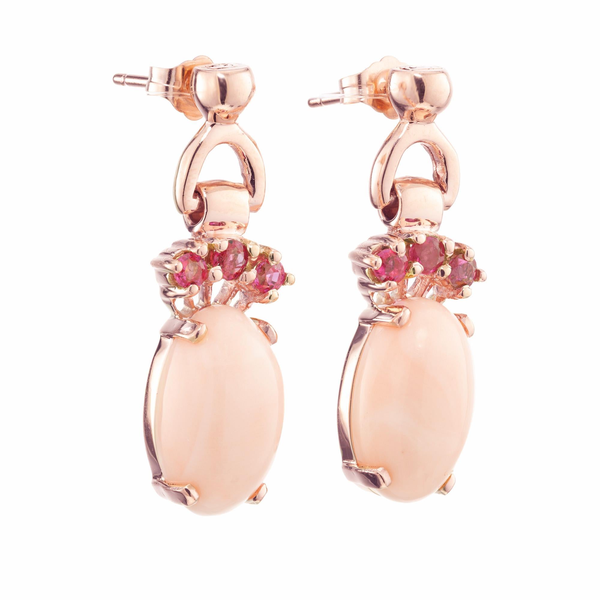 Elegante Retro Art Deco Korallen-Saphir-Ohrringe. Besetzt mit zwei ovalen rosafarbenen Korallensteinen mit einem Karatgewicht von 12,25cts, montiert in 14er Roségold. Jede Koralle ist mit 3 runden rosaroten Saphiren verziert. Die Korallen sind gut