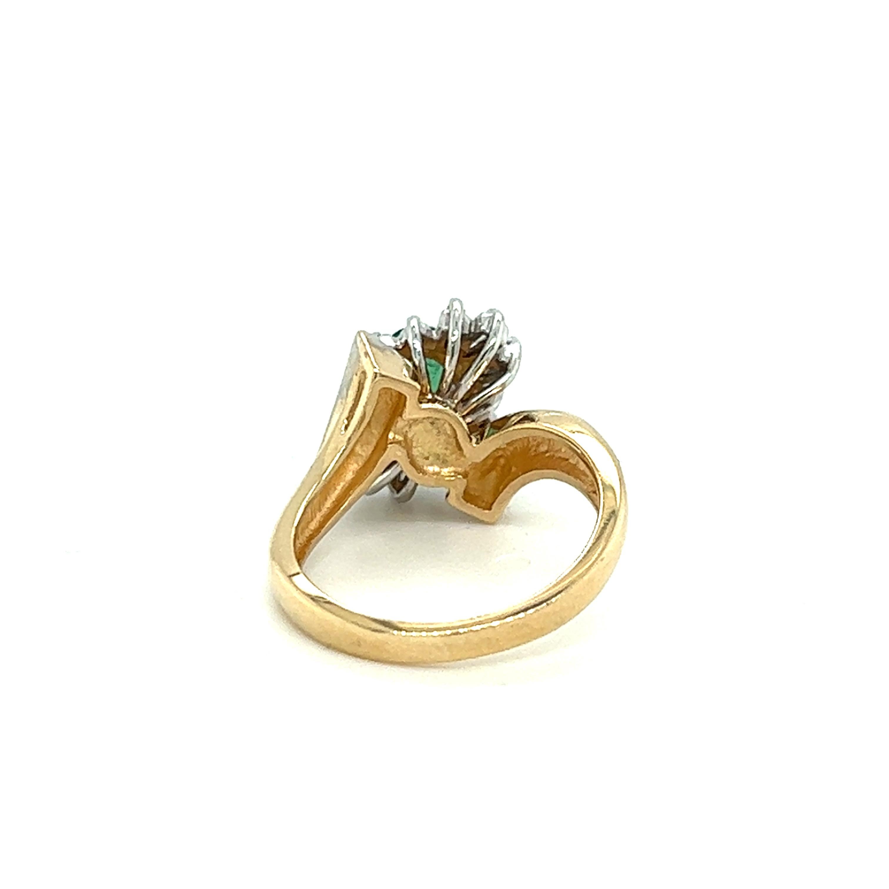 One 14 karat yellow and white gold (stamped 14K) bypass design ring set with one 7x5mm oval green emerald, six (6) baguette diamonds, approximately .10 carat total weight with matching H/I color and I1 clarity and eight (8) single cut diamonds,