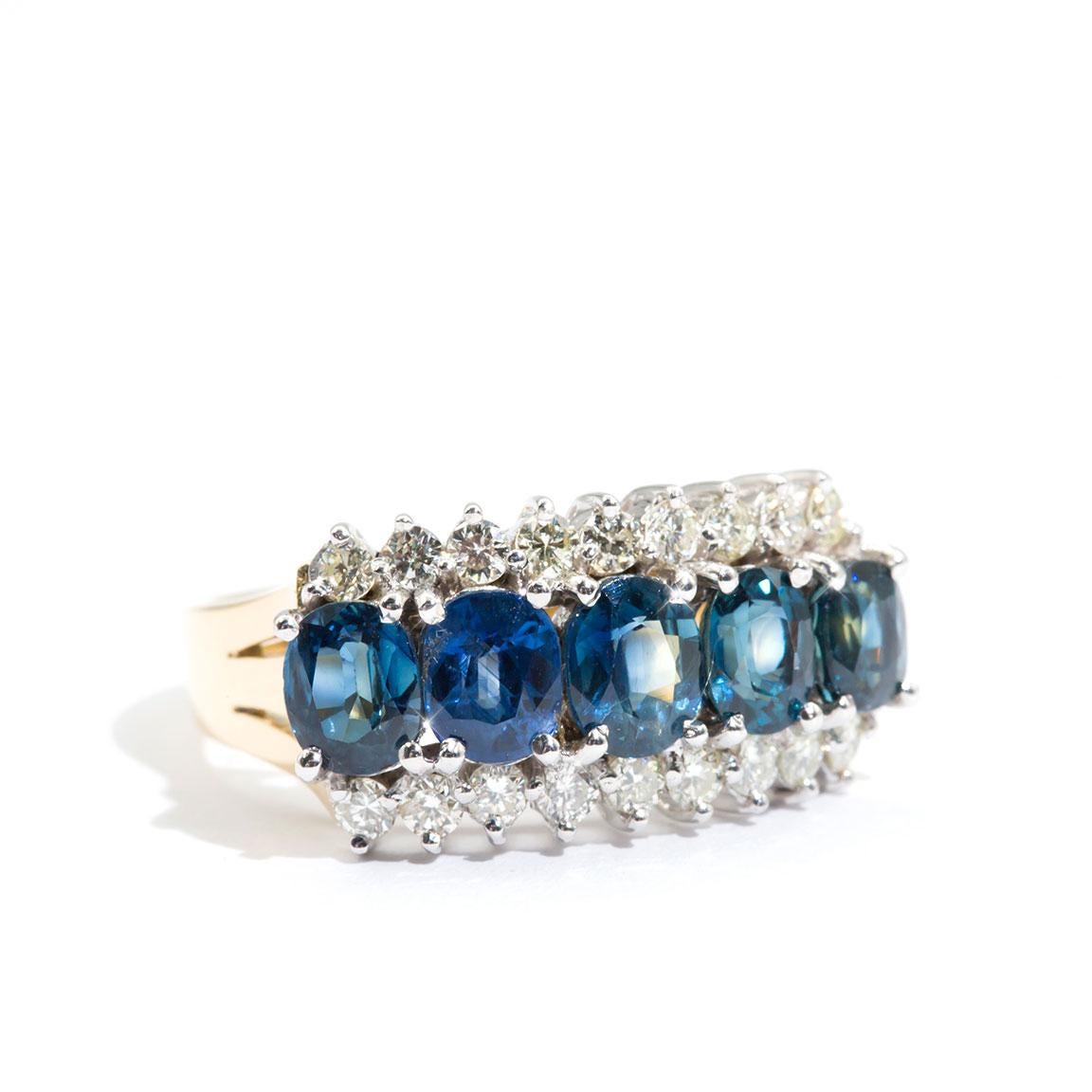 Carefully crafted in 18 carat gold is this enchanting vintage ring featuring five striking oval blue sapphires encompassed by 0.54 carats of sparkling round brilliant cut diamonds. We have named this gorgeous vintage splendour The Frankie Ring. The