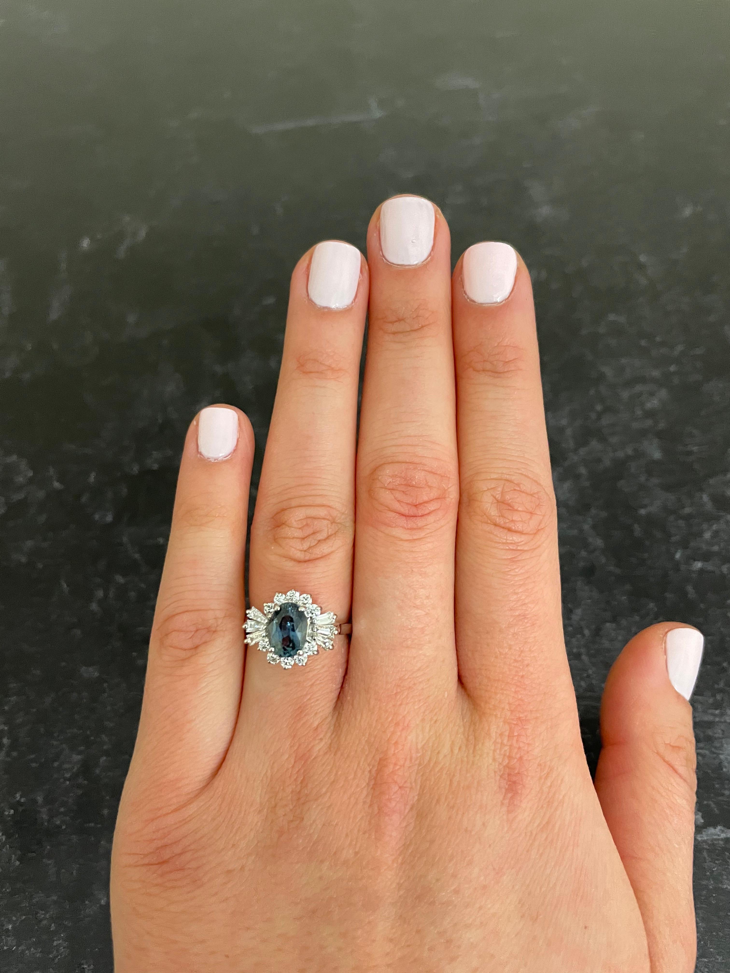 Material: 18k White Gold 
Center Stone Details: 1 Oval Shaped Blue/Green Sapphire at 1.72 Carats -Measuring 8.1 x 6 mm
Mounting Diamond Details : 6 Baguette Diamonds at 0.28 Carats - Clarity: VS-SI / Color: G-H
Diamond Details: 10 Brilliant Round