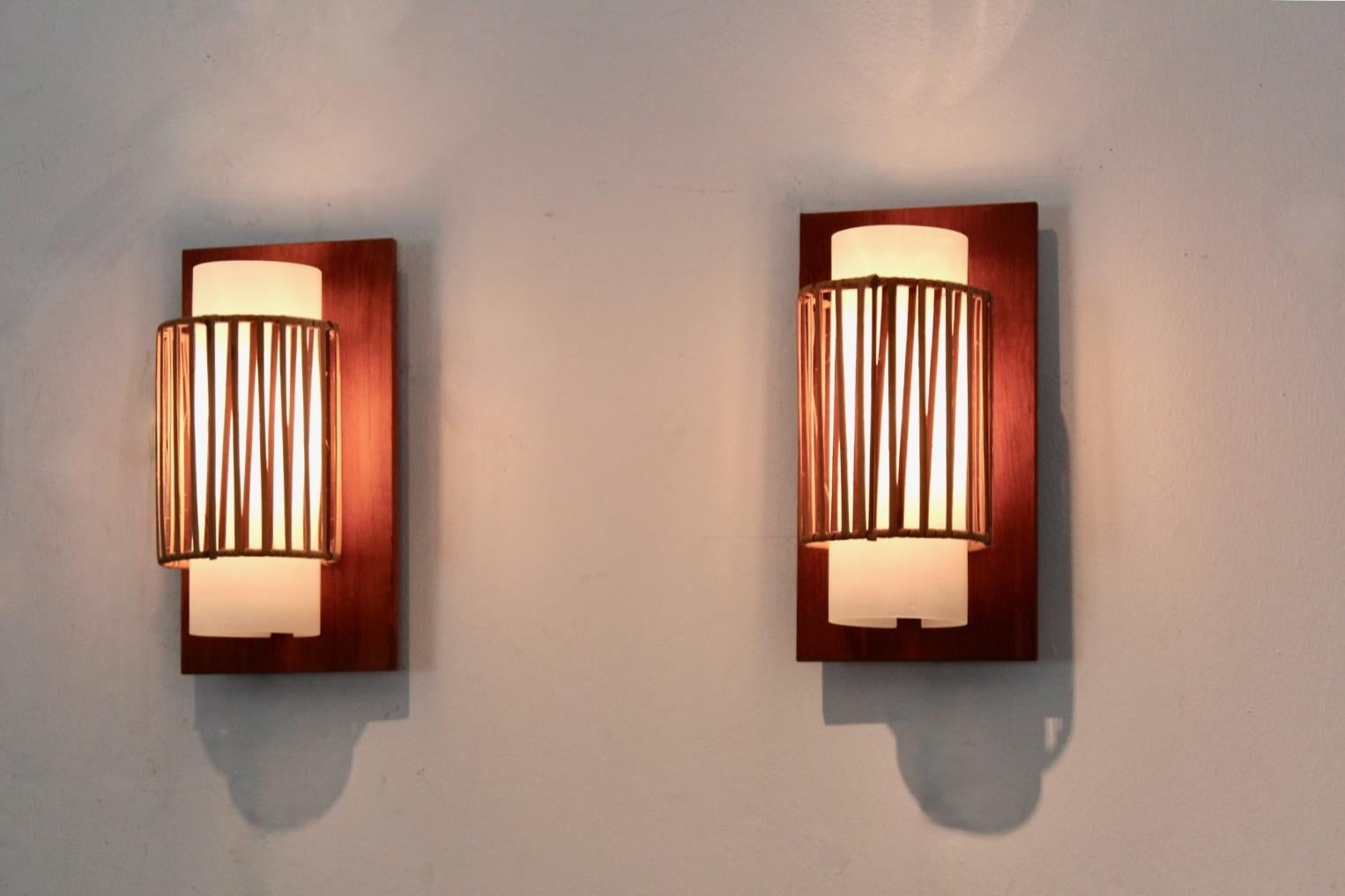 Sofisticata coppia di applique in vetro opalino con paralume in rattan naturale trasparente prodotta nei Paesi Bassi negli anni '60. Questo set è disponibile in una versione molto rara e mai vista. Ogni lampada ha una bella piastra posteriore