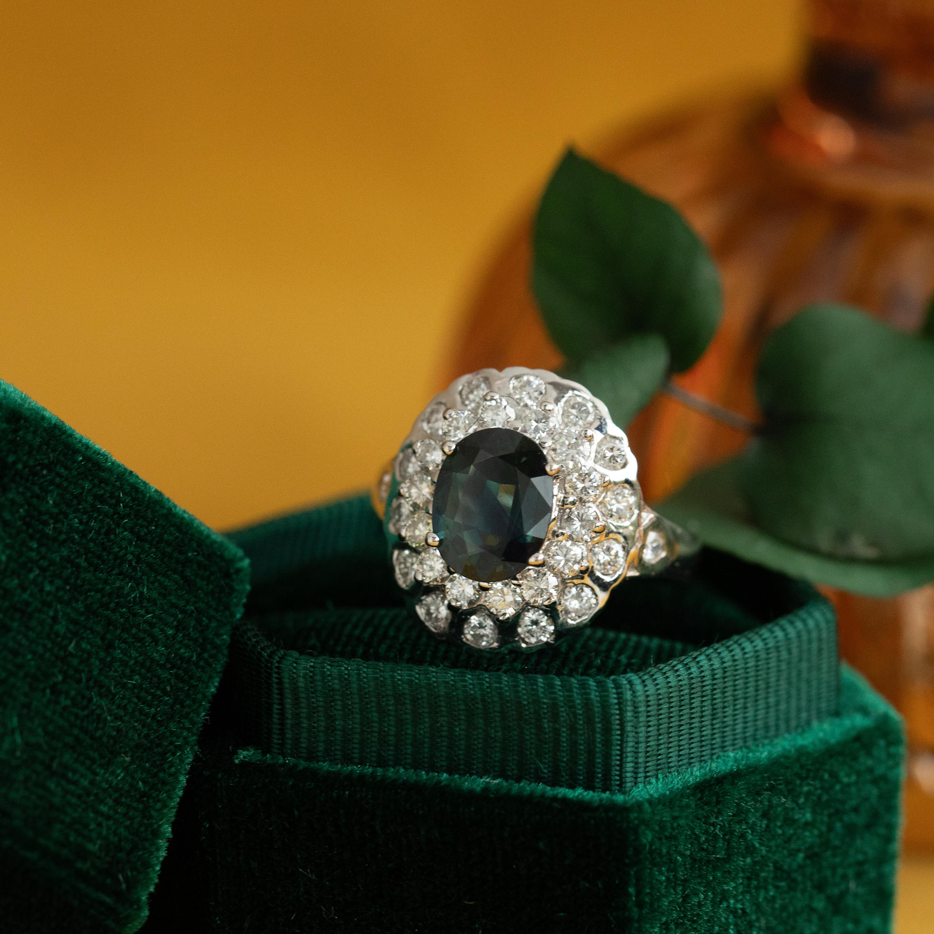 Centrally set with a beautiful parti sapphire, this ring is crafted from solid 18K white gold and features 1.25 carats total of natural diamonds. The parti sapphire displays exquisite coloration, ranging from teal to blue to more green in places. In