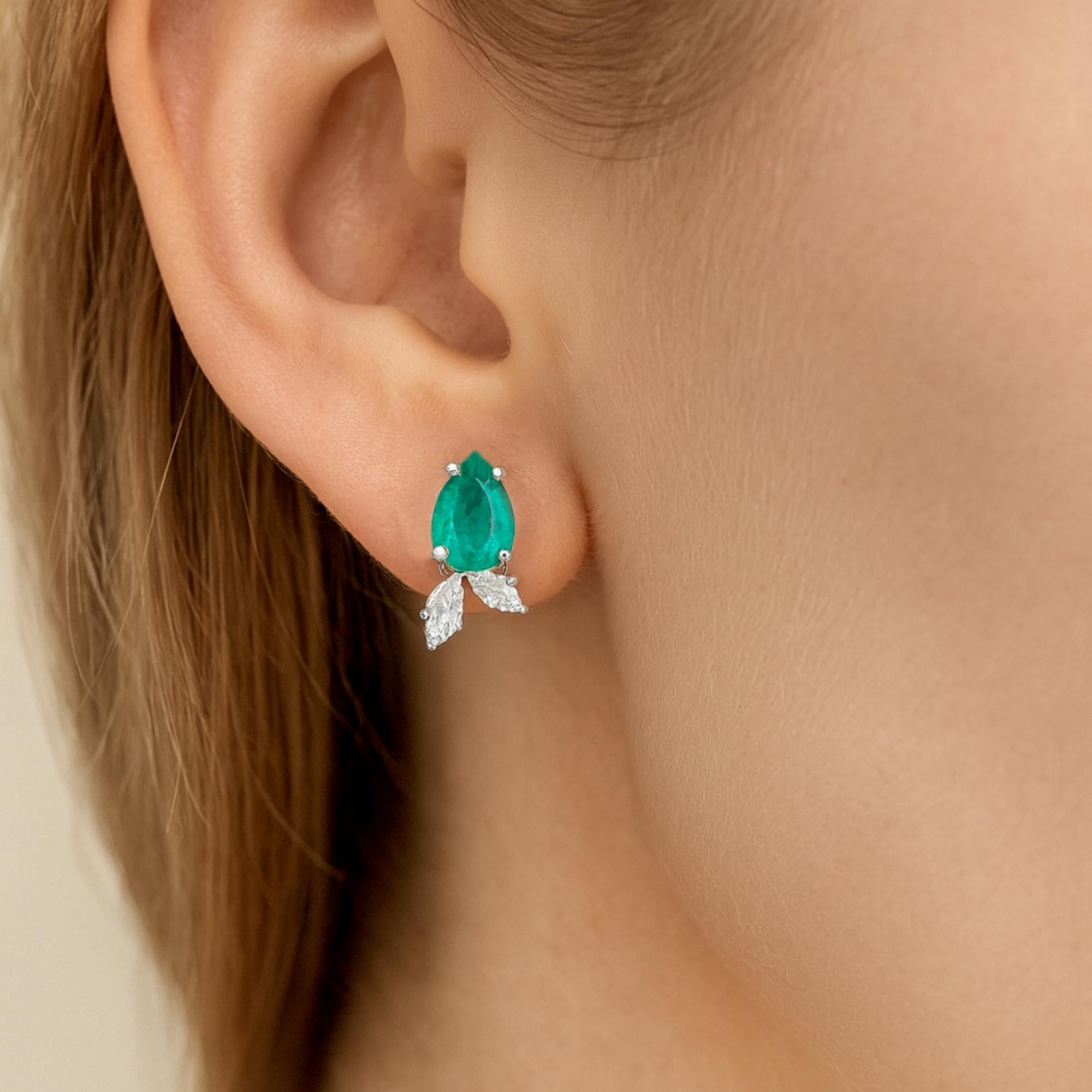 Questi orecchini a perno in oro bianco 14 carati con diamante smeraldo a pera sono caratterizzati da due diamanti a taglio marquise incastonati sotto lo smeraldo, uno piccolo e uno grande che imita la foglia. 
Gli smeraldi sono simboli di amore,