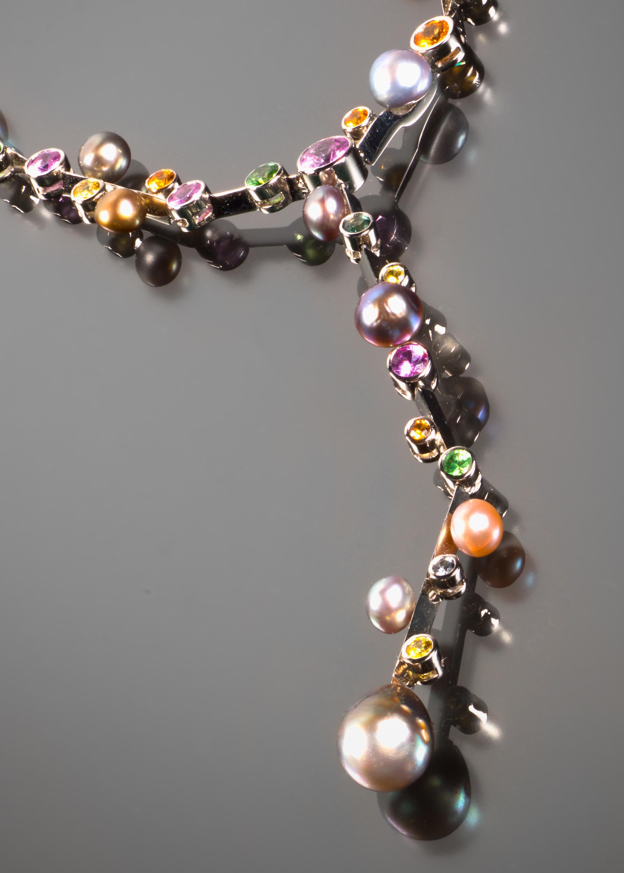 This sophisticated gem set necklace takes a modern approach to colored stones. Vived-hued sapphires in shades of pink, green, blue, orange and yellow are randomly placed along a flexible white gold necklace, while rare natural pearls of varying