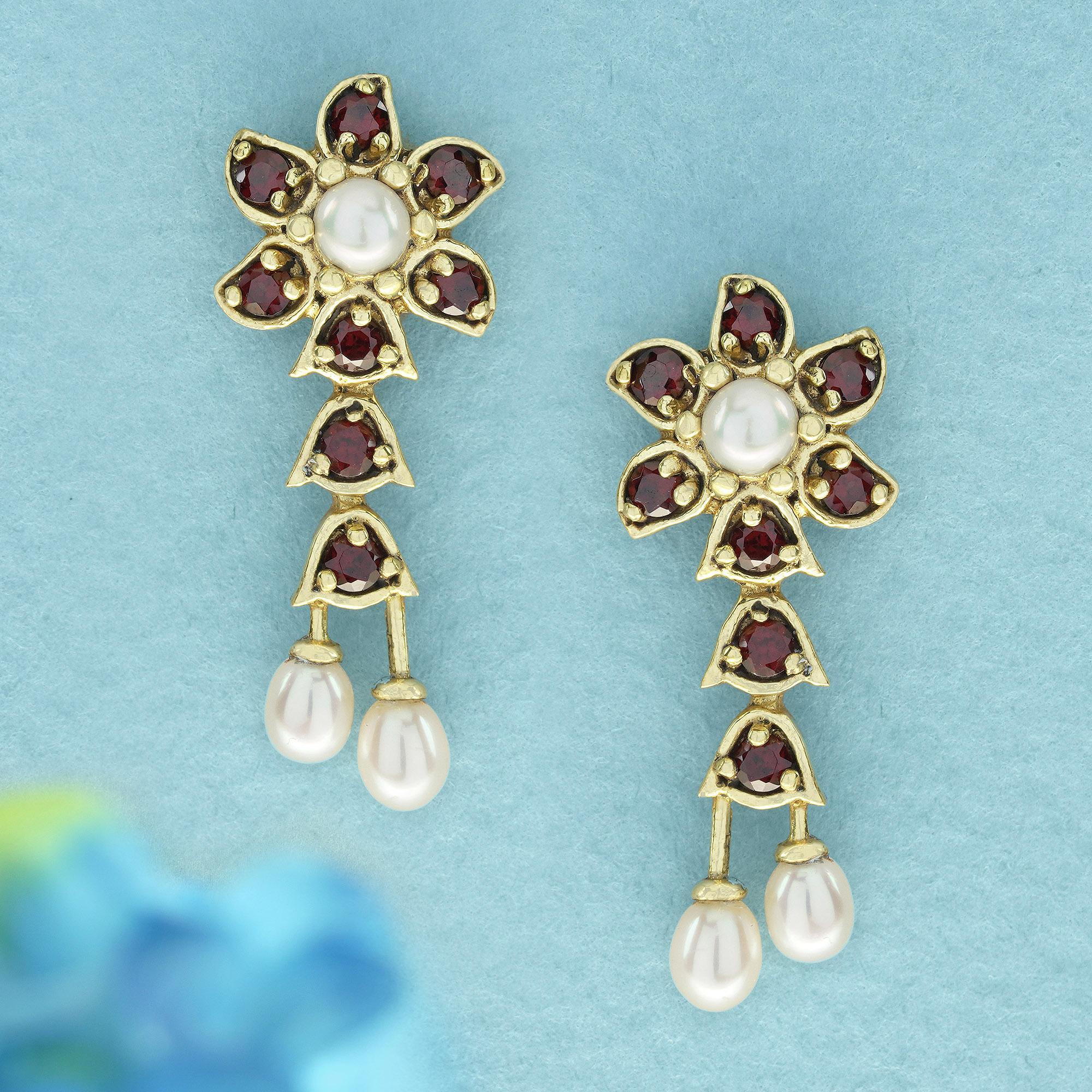 Tauchen Sie ein in die Welt des Vintage-Glamours mit diesen bezaubernden Ohrringen. Inspiriert von der Eleganz der Natur, zieren verschlungene Blumenmuster das Design. Jeder Ohrring besteht aus einer leuchtenden weißen Perle, die von runden roten