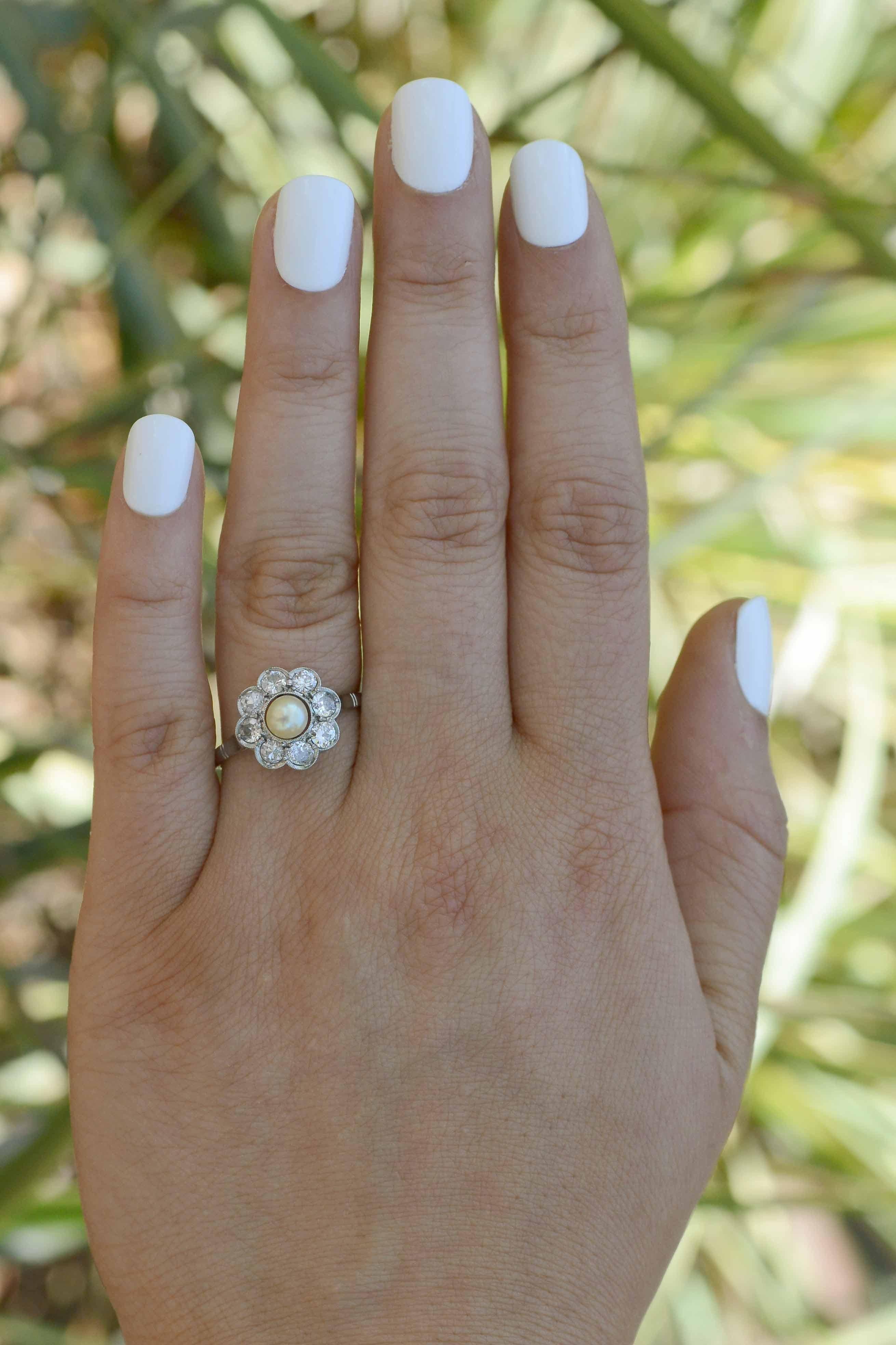 The Granville natural pearl and diamond antique engagement ring is simply stunning. Centering upon a 5 mm creamy, lustrous, light golden natural pearl that seemingly floats in a halo setting. The sea of surrounding diamonds creates a flower cluster