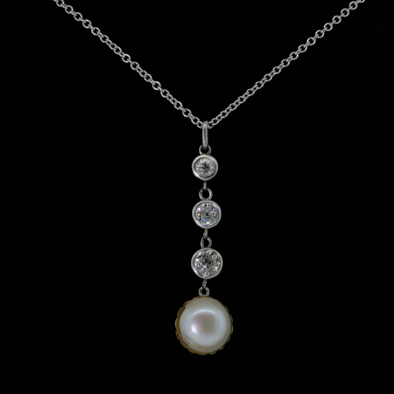A beautiful coveted platinum top, articulated pendant that features three Old Mine Cut Diamonds weighing 0.60 carat; set in 14KT yellow gold bezels.  A dangling layered Natural Pearl is set on a yellow gold clam shell cup.  The beautiful Pearl