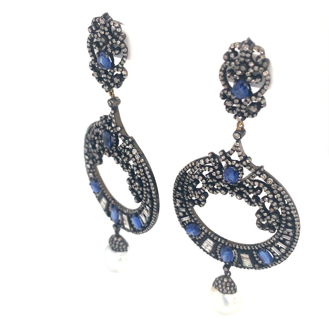 A stunning set of earrings consisting of a 16.74-carat natural pearl, 4.46-carat kyanite, and a natural 6.05-carat diamond all set in silver. 
