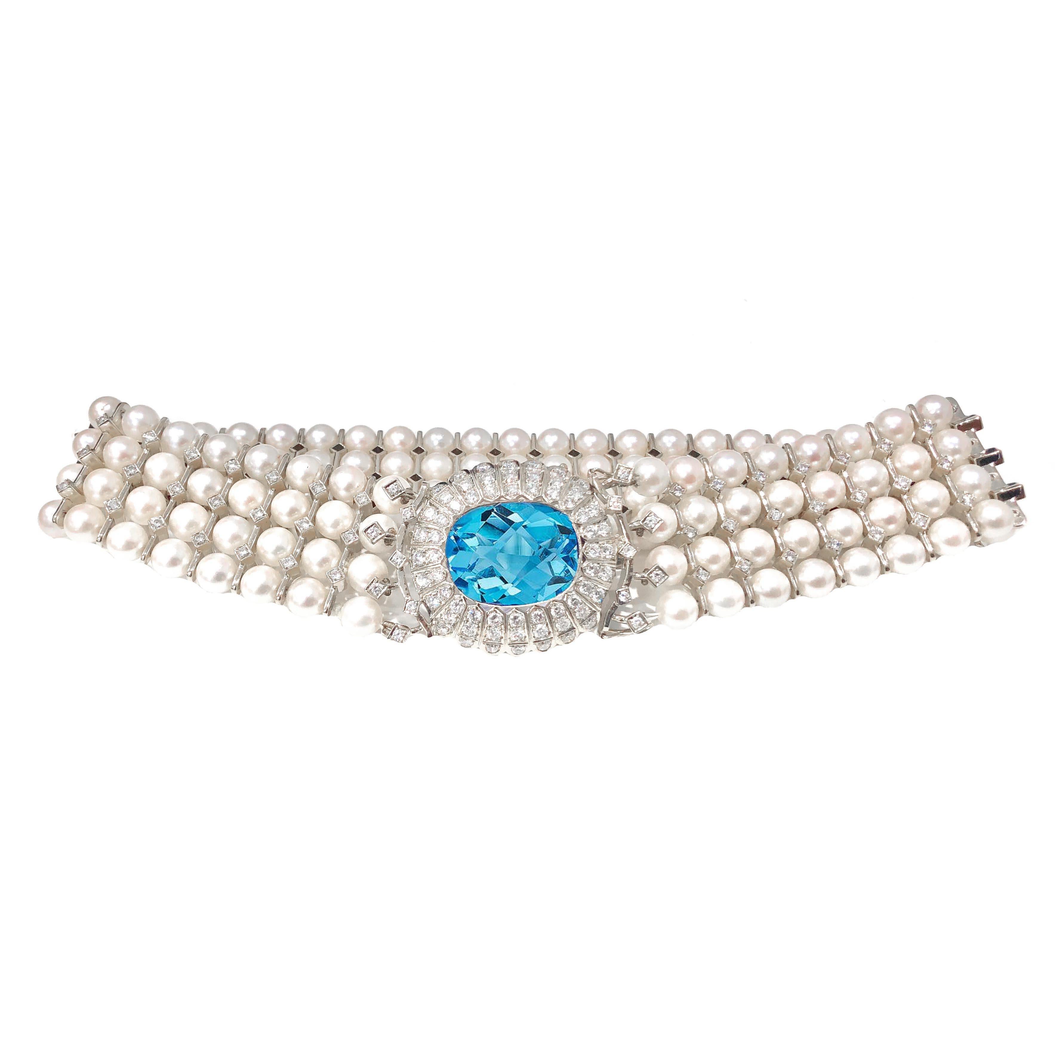 Art Deco, 18 karat white gold, pearl, blue topaz and diamond collar necklace and bracelet set. The necklace has an estimated 7.00 carats total weight in diamonds, 20.00 + carat natural blue topaz center and 152 genuine pearls.
The bracelet has an