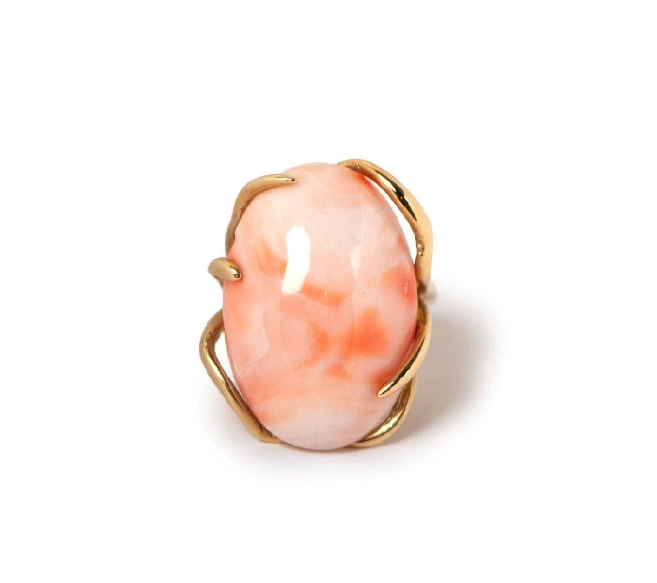 Centrée sur un corail rose naturel, cette bague artisanale est réalisée dans une monture en or massif 14K. Le cabochon ovale en corail mesure environ 2,5 cm (L) x 2 cm (l), serti pour mettre en valeur sa beauté organique. La bague mesure environ
