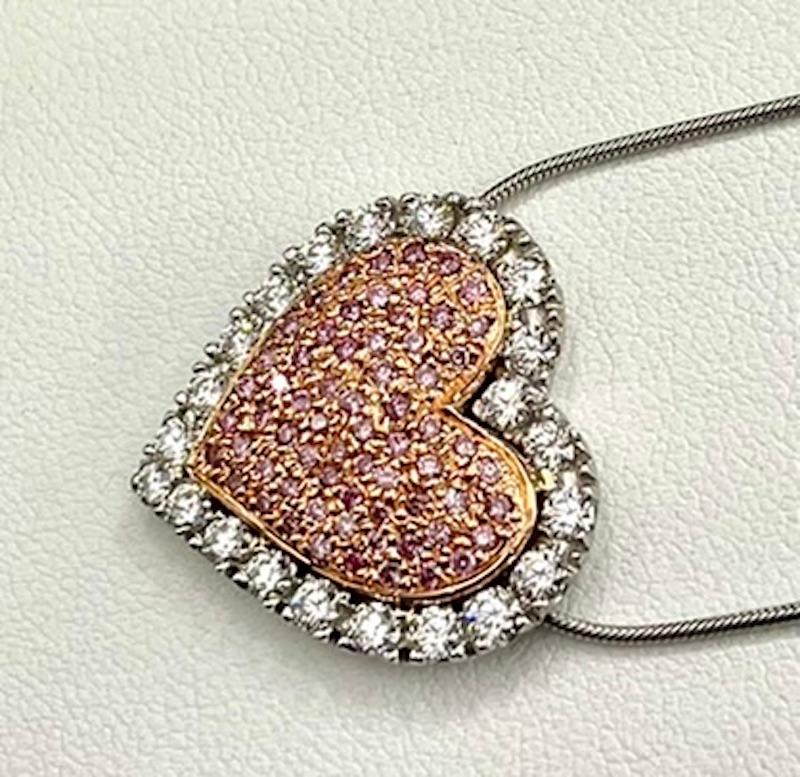 Natural Color Pink Diamonds are among the most rare of colors. This is a simple, elegant and classic heart shape pave set pendant, showcasing the romantic pink color of these diamonds. The carat weight of the pink diamonds is .57 and the surrounding