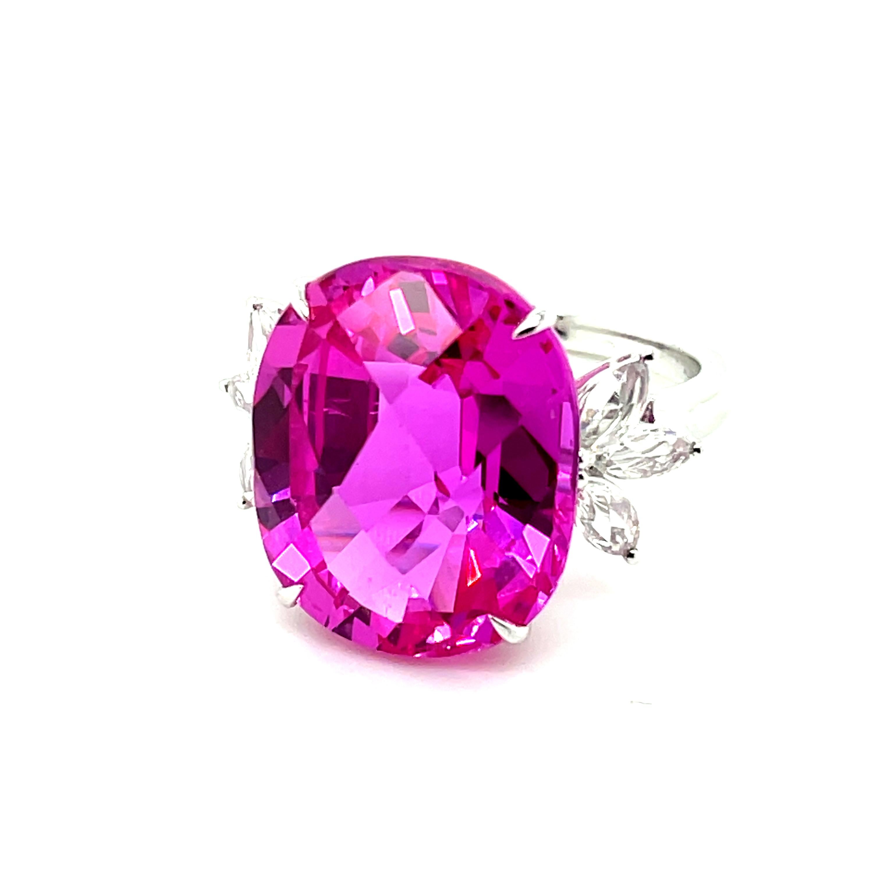 Centering a captivating Pink Topaz, weighing an impressive 20.57 carats, radiating a subtle and charming pink hue that is truly enchanting.

The Pink Topaz is gracefully complemented by a symmetrical arrangement.

It is shouldered by six Marquise