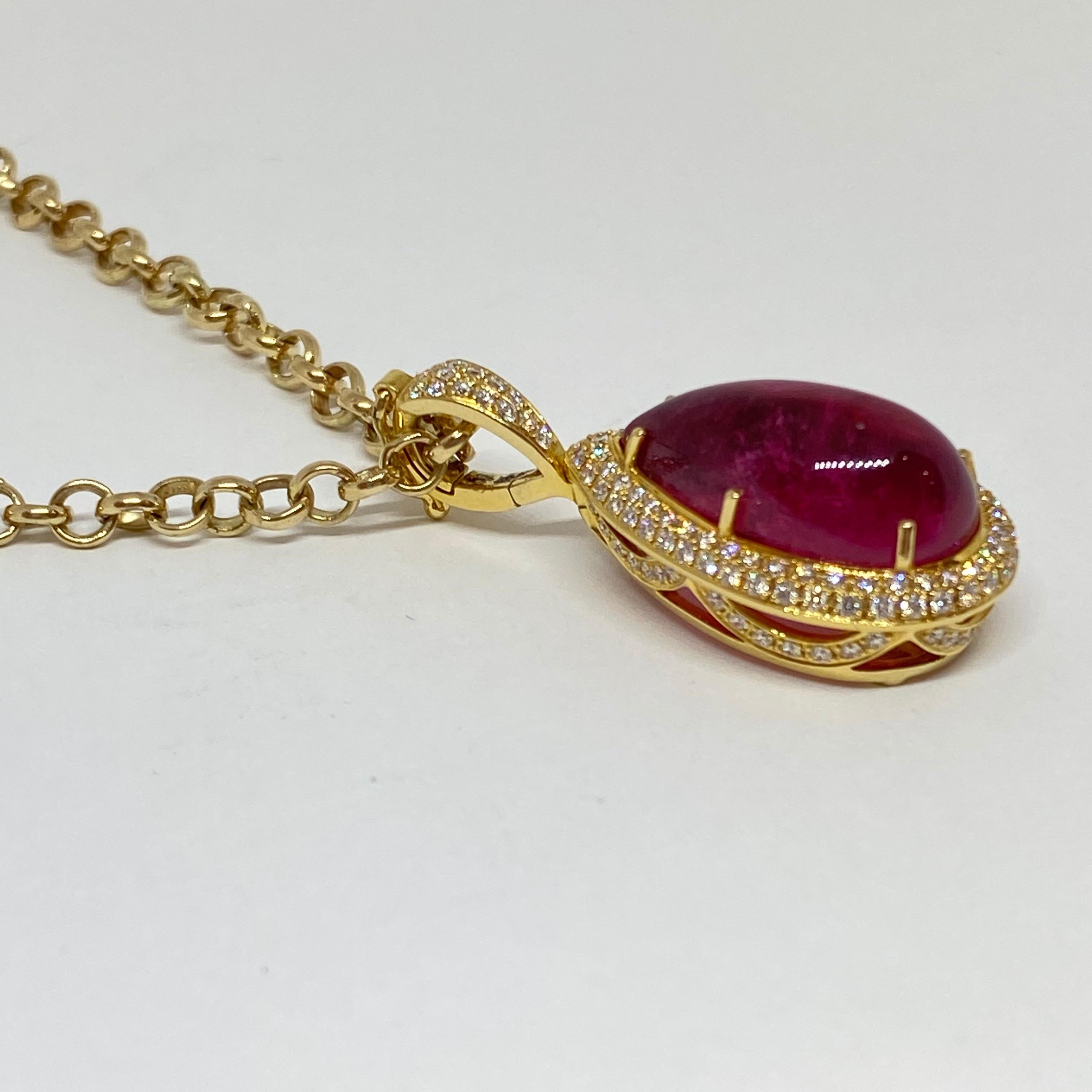 This unique pink tourmaline and diamond pendant is fashioned from 18 karat yellow gold. The pink tourmaline is a pear shape cabochon weighing 17.10 carats (12.6mm x 21.2mm) with a deep pink color. The tourmaline is set in six prongs, surrounded by