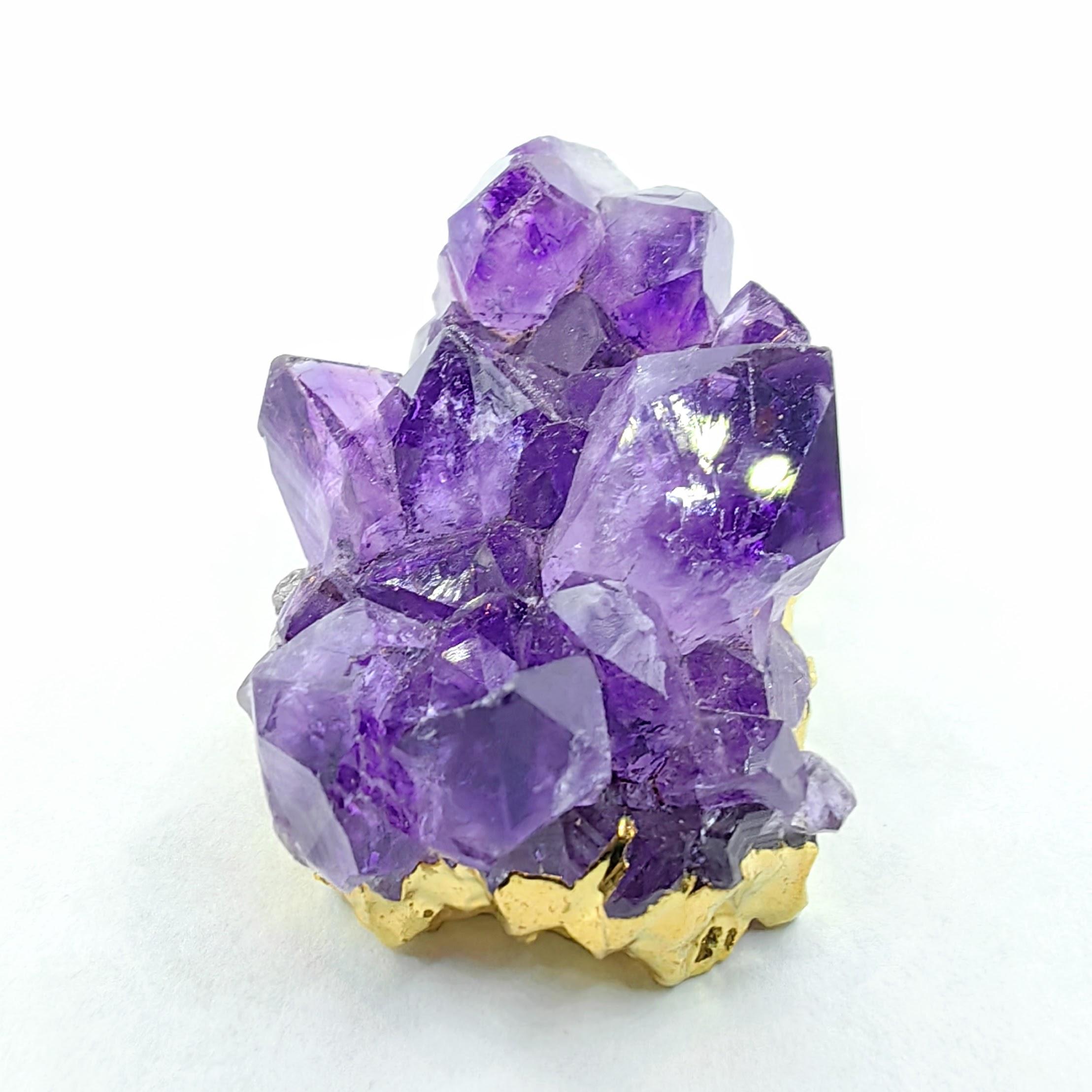 Eleva tu colección de joyas con este impresionante colgante de racimo de cristales de amatista en bruto, bellamente realzado con elegantes bordes chapados en oro. Esta pieza curativa única presenta cristales de amatista de color púrpura intenso