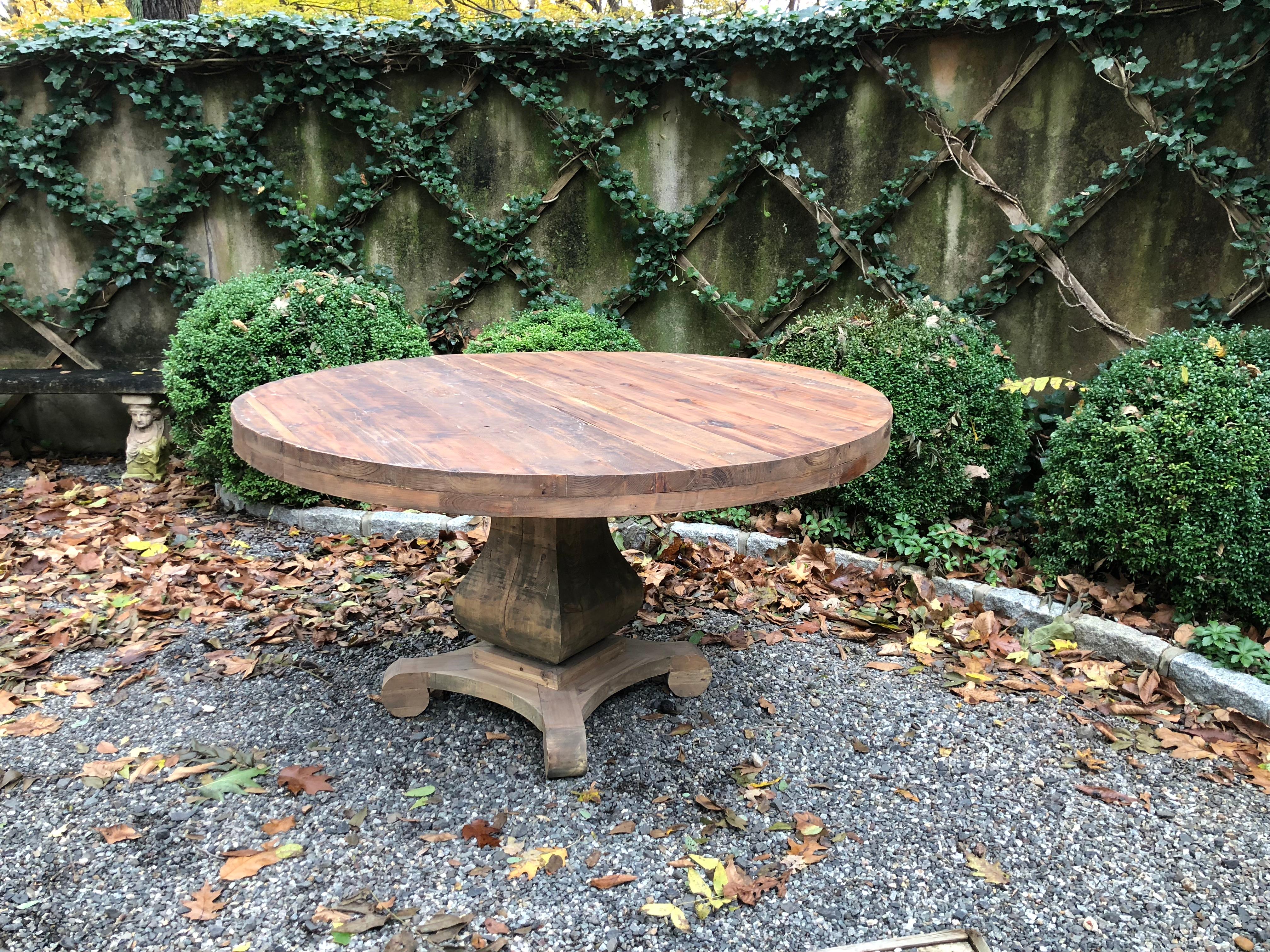 Handsome and rustic custom-made 60 inch round dining table made from reclaimed wood. A chunky, curved pedestal supports this one-of-a-kind table.   As shown, the colors and grain of the wood varies, adding to the natural beauty of this piece.