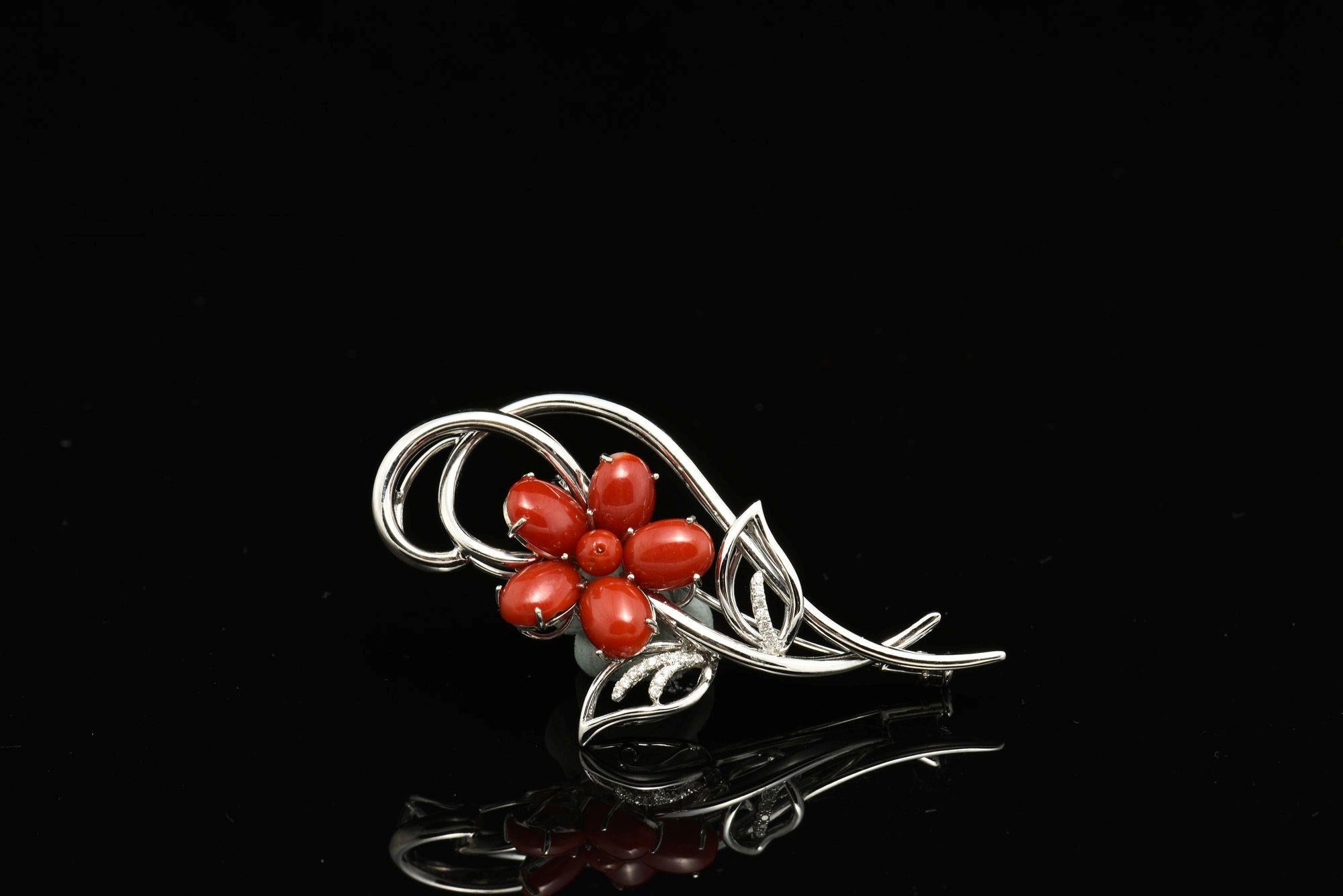 Centrée sur six perles de corail rouge naturel disposées en forme de fleur, cette pièce exquise est rehaussée de diamants naturels sertis comme de délicates feuilles, le tout réalisé à la main dans une monture en or 14 carats. Mesurant environ 6 x 3
