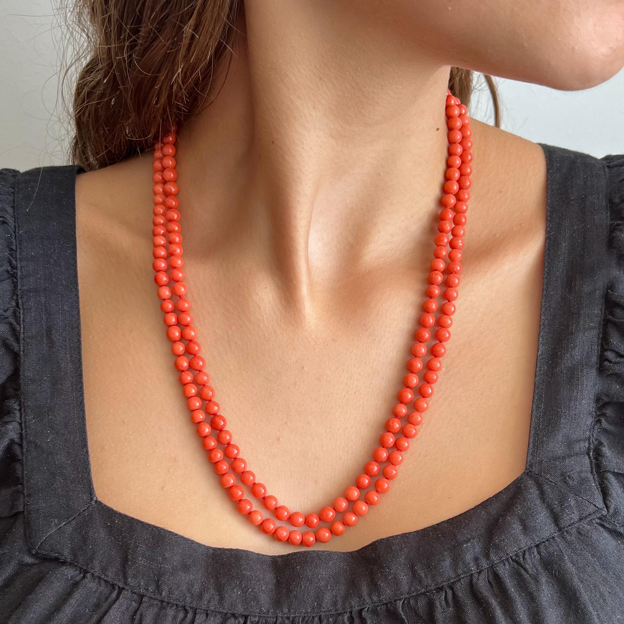 A vintage natural coral and 14 karat gold two-strand beaded necklace. The coral beads of this necklace are round-shaped and set with a beautiful oval-shaped clasp created in 14 karat gold. The color hue of the coral tends to salmon - this applies to