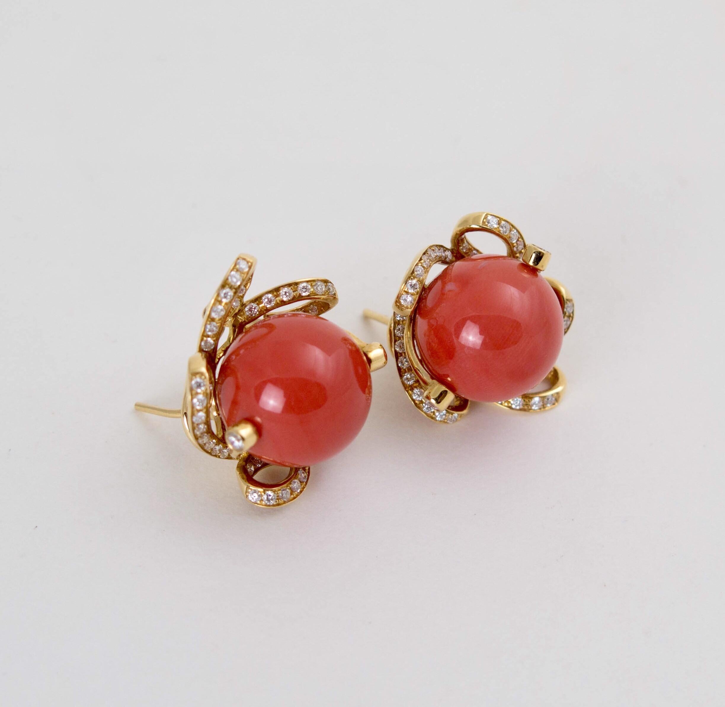 A beautiful pair of natural coral, 18k yellow gold and diamond earrings. 

The earrings each centered around a large round coral bead of exceptional and even reddish orange color surrounded by an undulating ribbon setting in 18k yellow gold and
