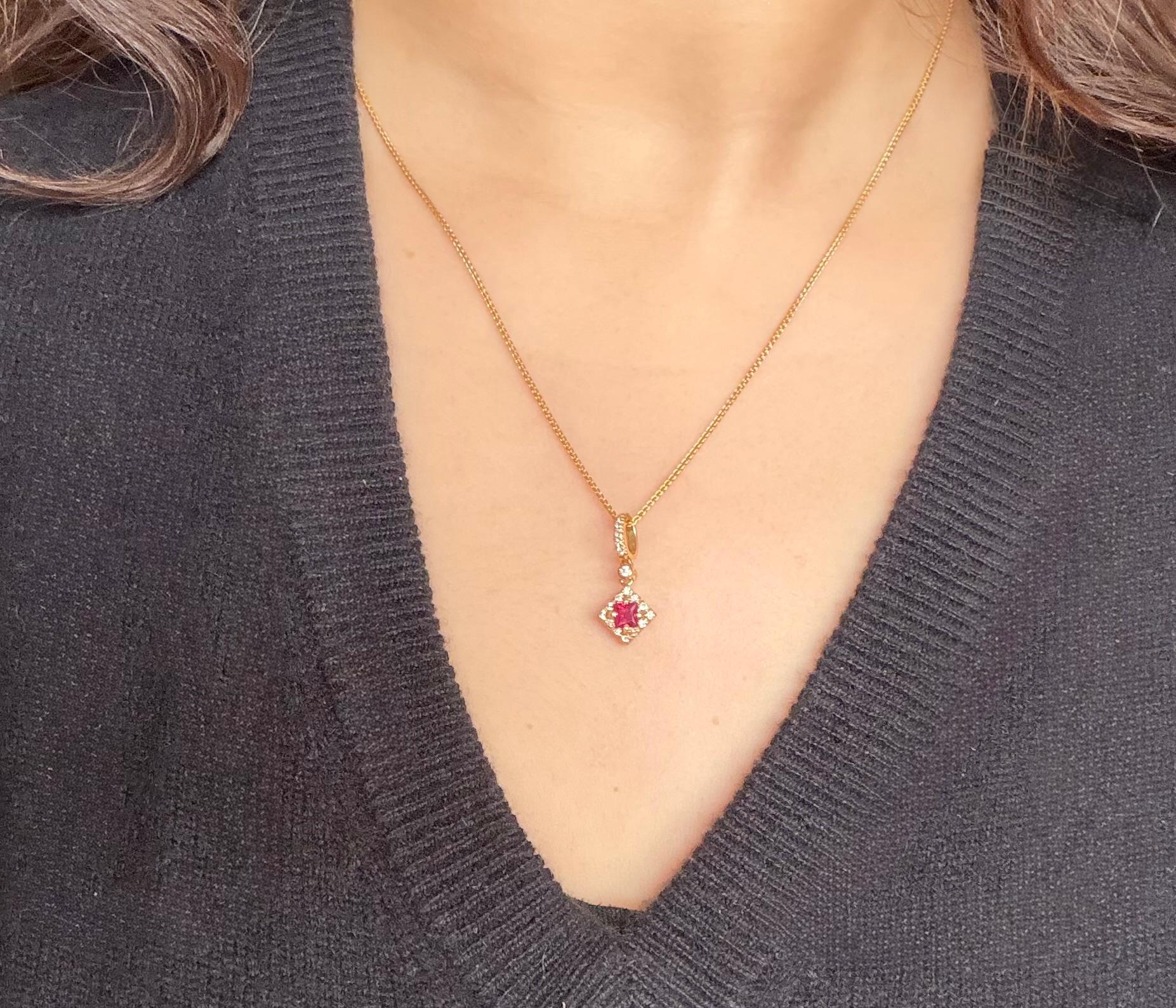 Un rubino rosso naturale di forma quadrata di 4 mm si trova al centro di questa elegante collana con ciondolo, circondato da diciannove diamanti rotondi a taglio brillante per un totale di circa 0,21 carati, colore H, purezza SI. Incastonato in oro