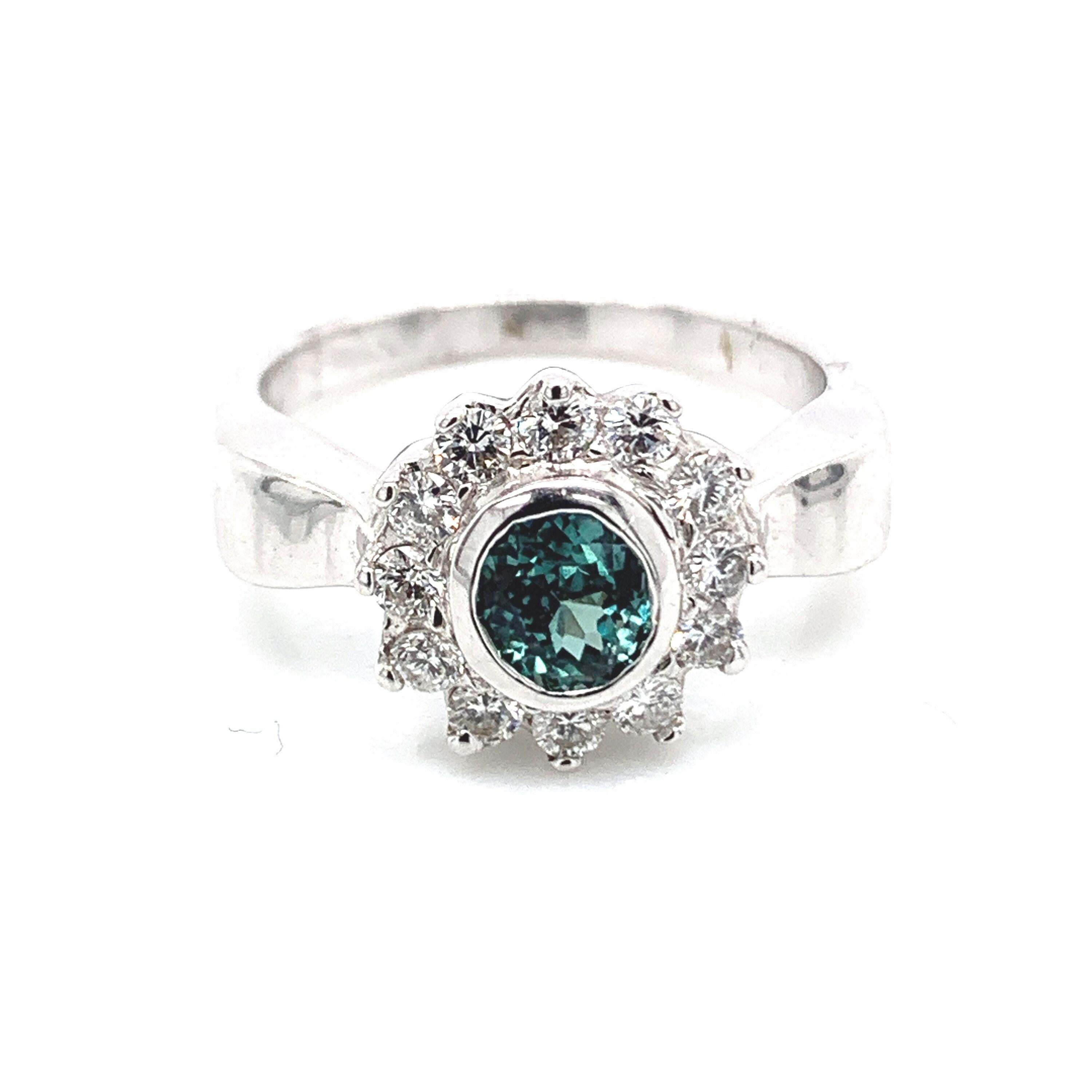 This is a gorgeous natural AAA quality round Alexandrite surrounded by dainty diamonds that are set in a vintage platinum setting. This ring features a natural 1.01 round alexandrite surrounded by a halo of trillion cut white diamonds. The ring is a