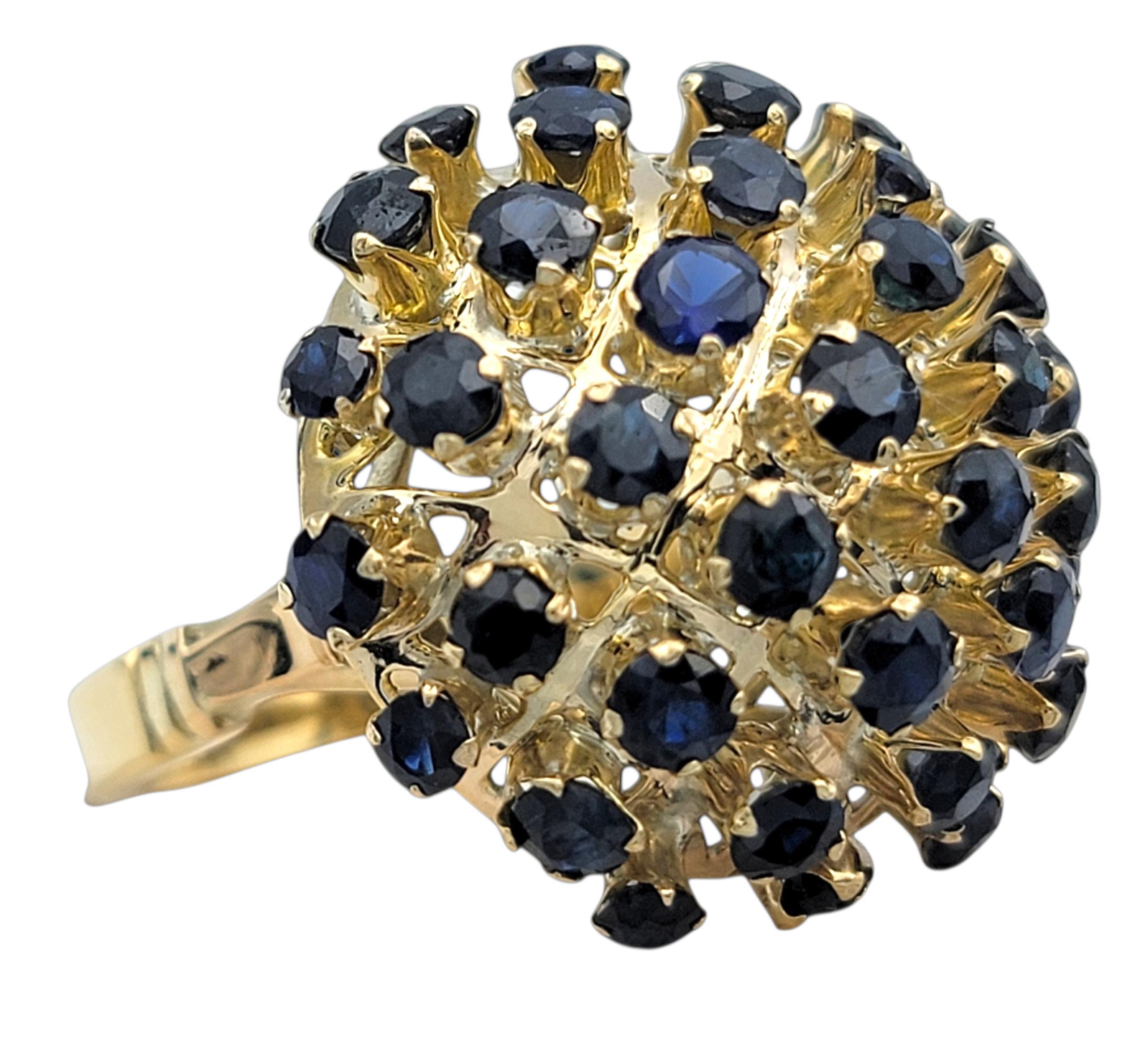 Cette bague présente une grappe audacieuse de saphirs d'un bleu profond, disposés en forme de dôme arrondi qui attire immédiatement le regard. Chaque saphir est serti individuellement, créant une surface texturée à la fois sculpturale et raffinée.