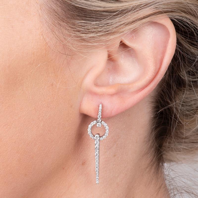 These geometric and contemporary dangling earrings feature 1.00 carat total weight in natural round diamonds set in 14 karat white gold. Friction post and back. 
Measurements: Length approximately 1.5