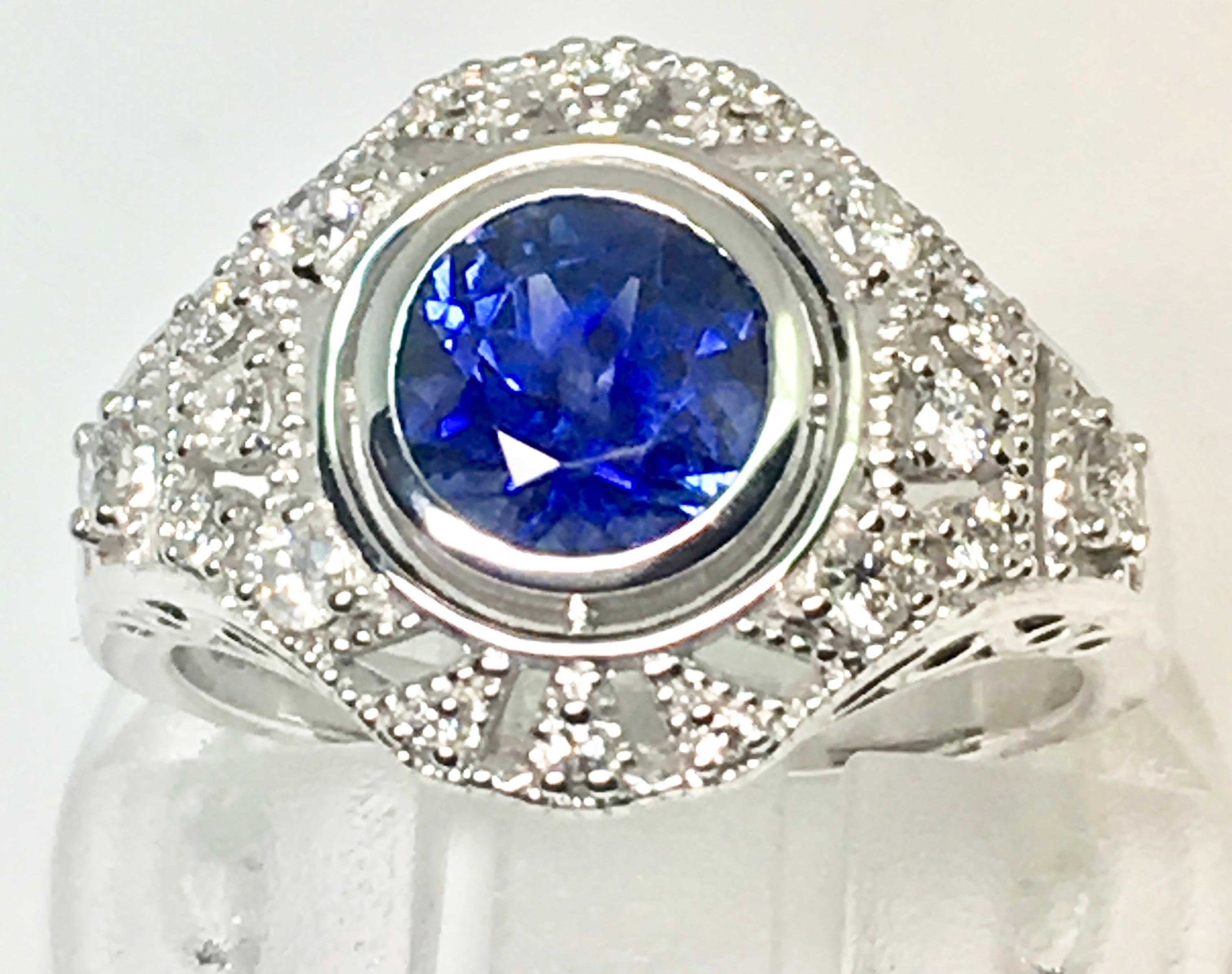 A Natural round sapphire weighing...  origin.... .This gorgeous velvet blue sapphire is rub over set in 18ct white gold. The central stone is surrounded by a cluster of  diamonds  and diamonds a third of the way down the shank. it design we wanted