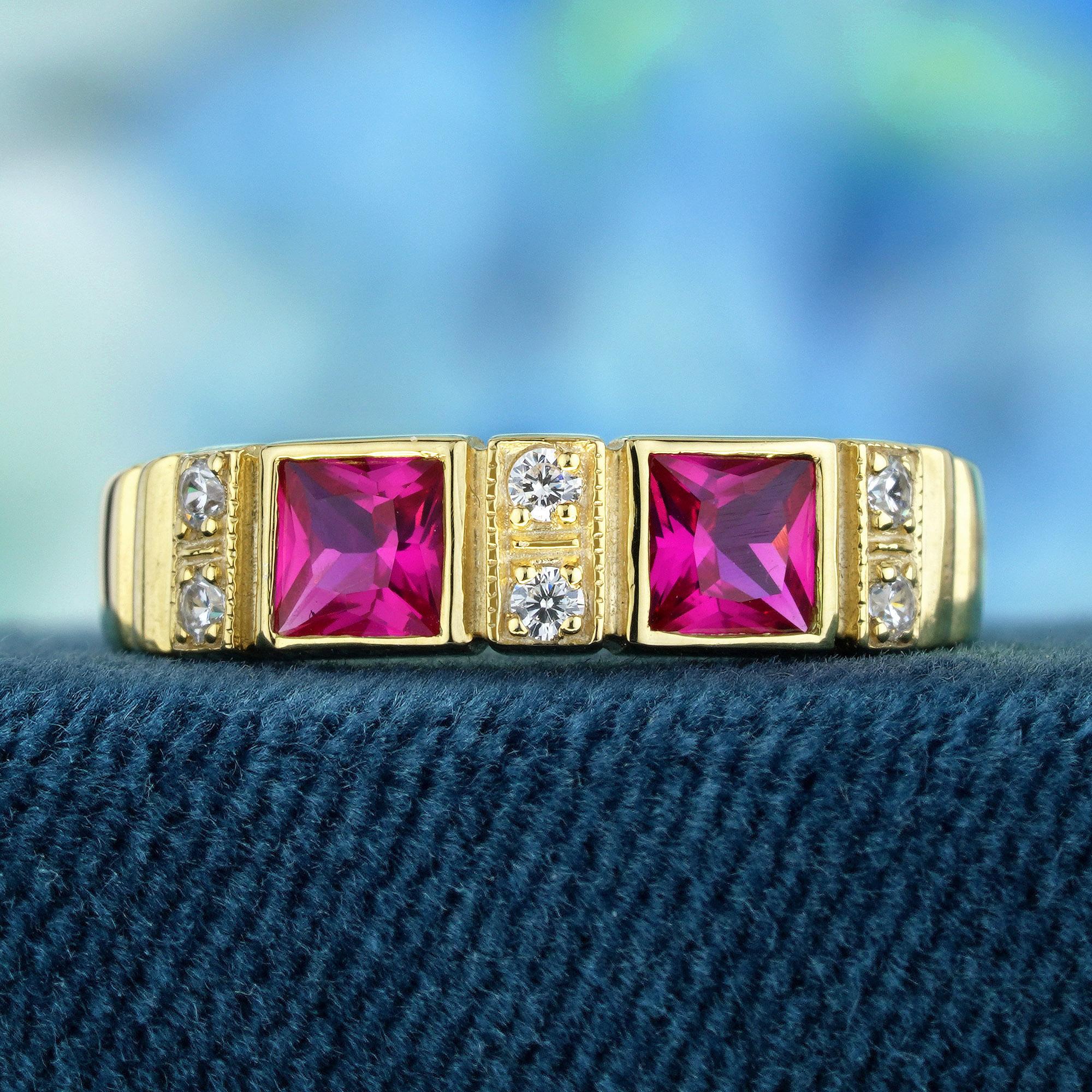 Cette fantastique bague à deux pierres en rubis présente deux rubis rouges de forme carrée, flanqués de six diamants. Magnifiquement réalisé en or jaune avec de délicats milgrain et gravures. Une éblouissante pièce vintage d'inspiration Art of
