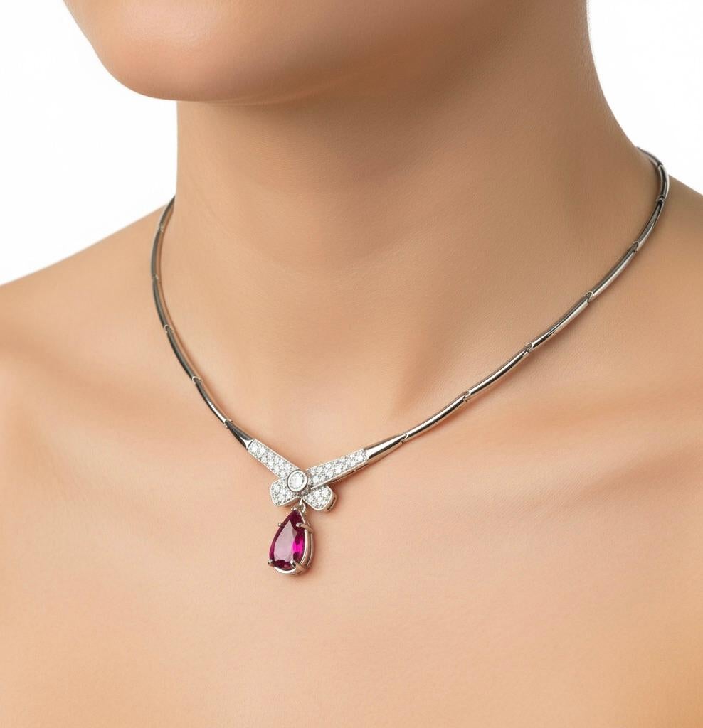 Collana ESTATE con al centro un rubino naturale del Mozambico con taglio a pera del peso di 2,30 carati, non trattato. Il rubino è incastonato in una splendida montatura a volute di ispirazione vintage. Il design del fiocco centrale della collana