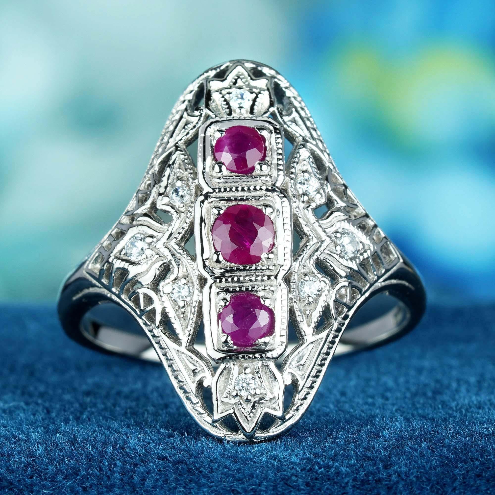 This Art Deco vintage-style ring. It features a central 3 cascading cluster of round red ruby set in a raised bezel, with delicate filigree work adorning the solid white gold band and shoulders adds a touch of femininity and romance to the ring. The