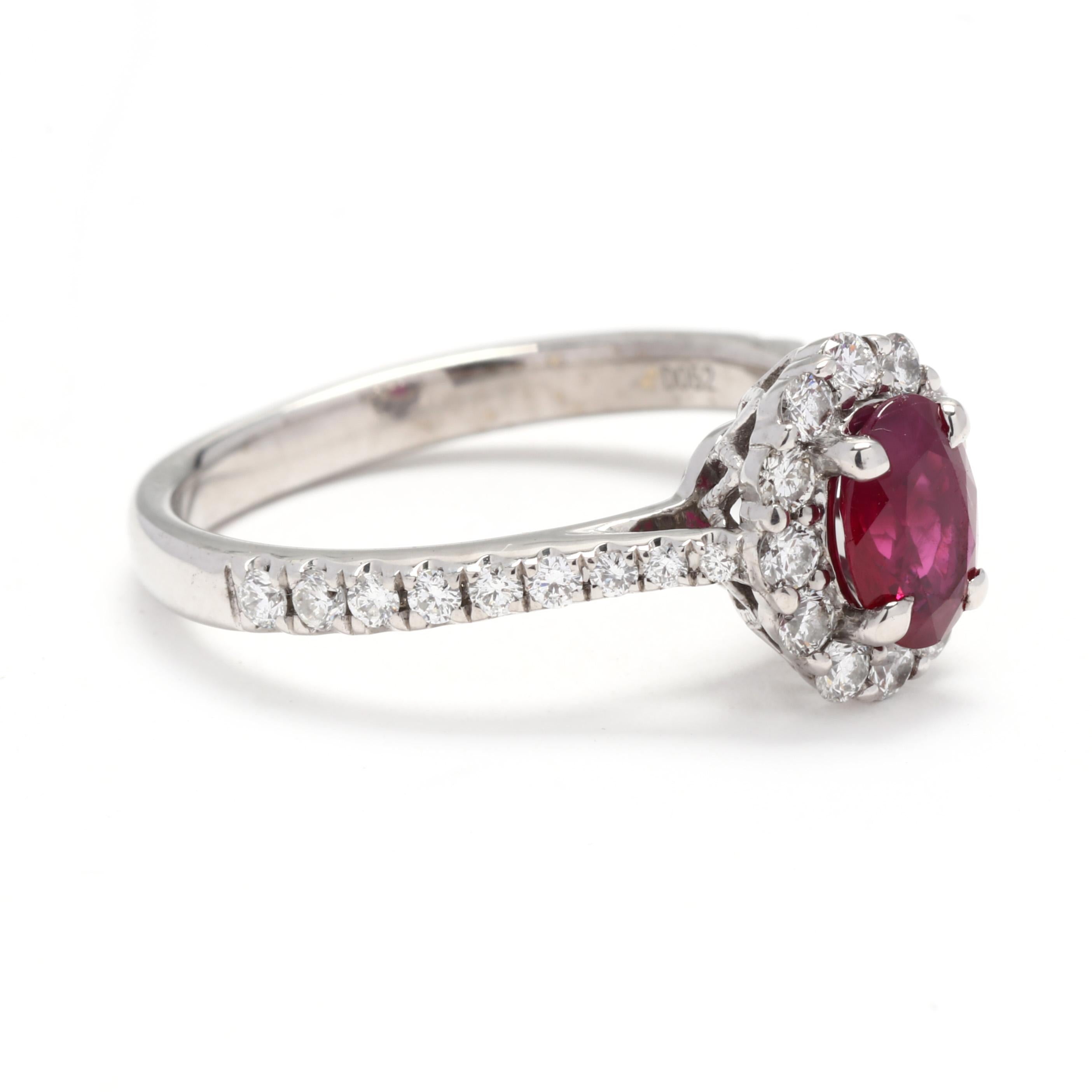 A 14 karat white gold natural ruby and diamond halo engagement ring. This July birthstone ring features a prong set, oval cut ruby weighing approximately 1.1 carat surrounded by a halo of round brilliant cut diamonds and down the band weighing