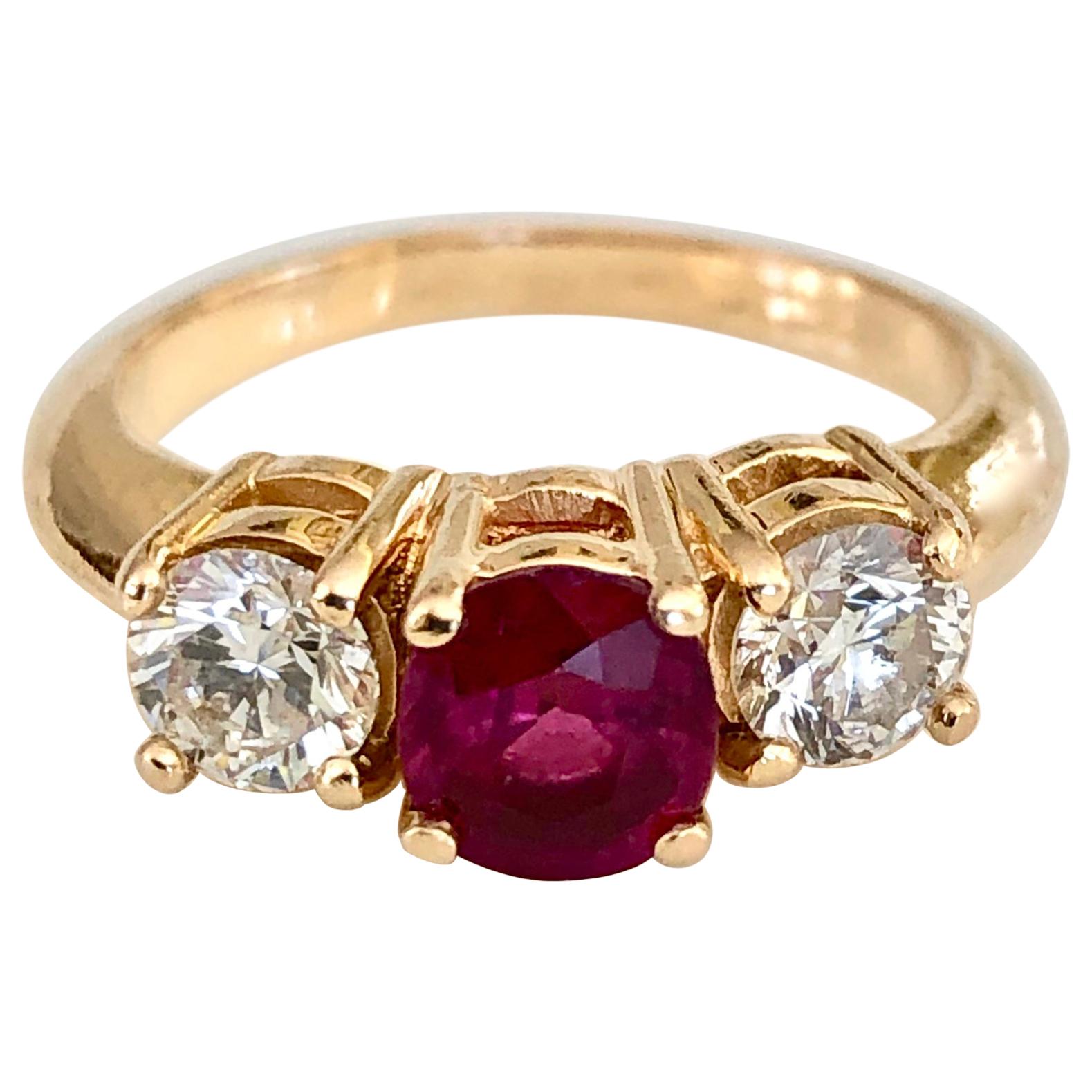 A classic trilogy engagement ring stars a natural deep, rich red ruby weighing 1.04 carat flanked by a matched pair of brilliant-cut diamonds G-H/SI1 weighing over 0.70 carats. This elegant ring is crafted in a timeless, traditional style of 18K