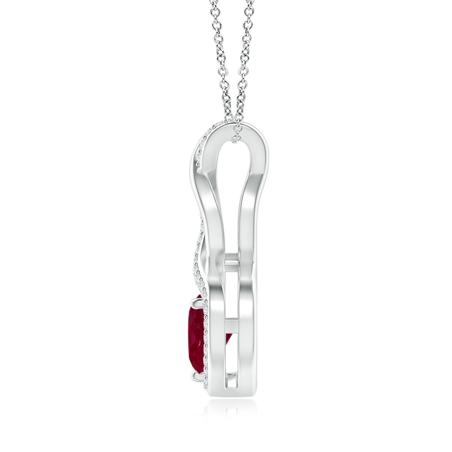 Una tira tachonada de diamantes se entrelaza con una tira de metal brillante para formar un ornamentado infinito. En medio del elegante infinito flota un rubí rojo en forma de corazón en un engaste de garras. Los brillantes diamantes infunden un
