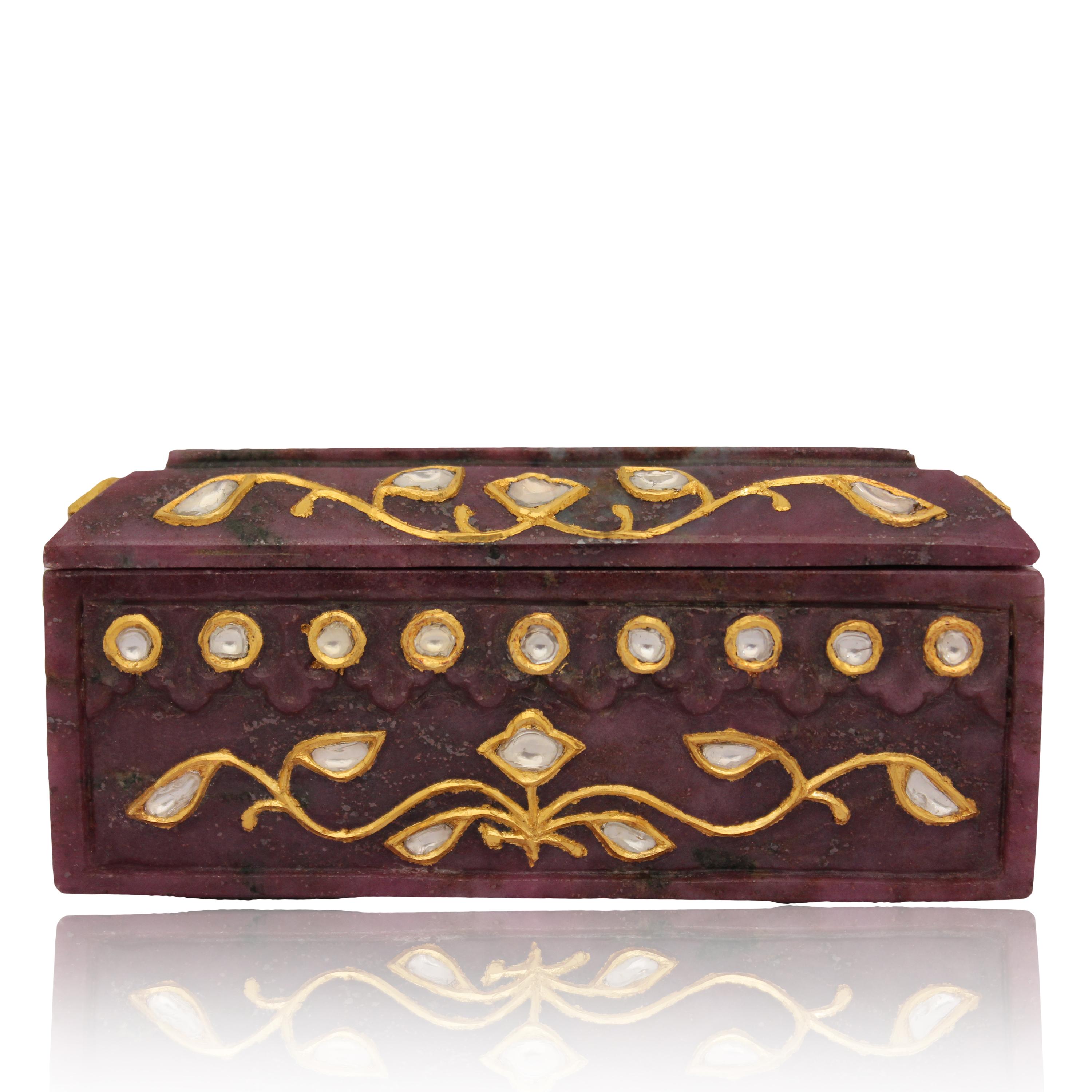 Natural Ruby box carved from one piece standing on four bracket feet, the lid carved in form of tapered roofs of Indian buildings with a flower at the centre inlaid with natural uncut diamond polkis. the box is encrusted in kundan technique on all 4