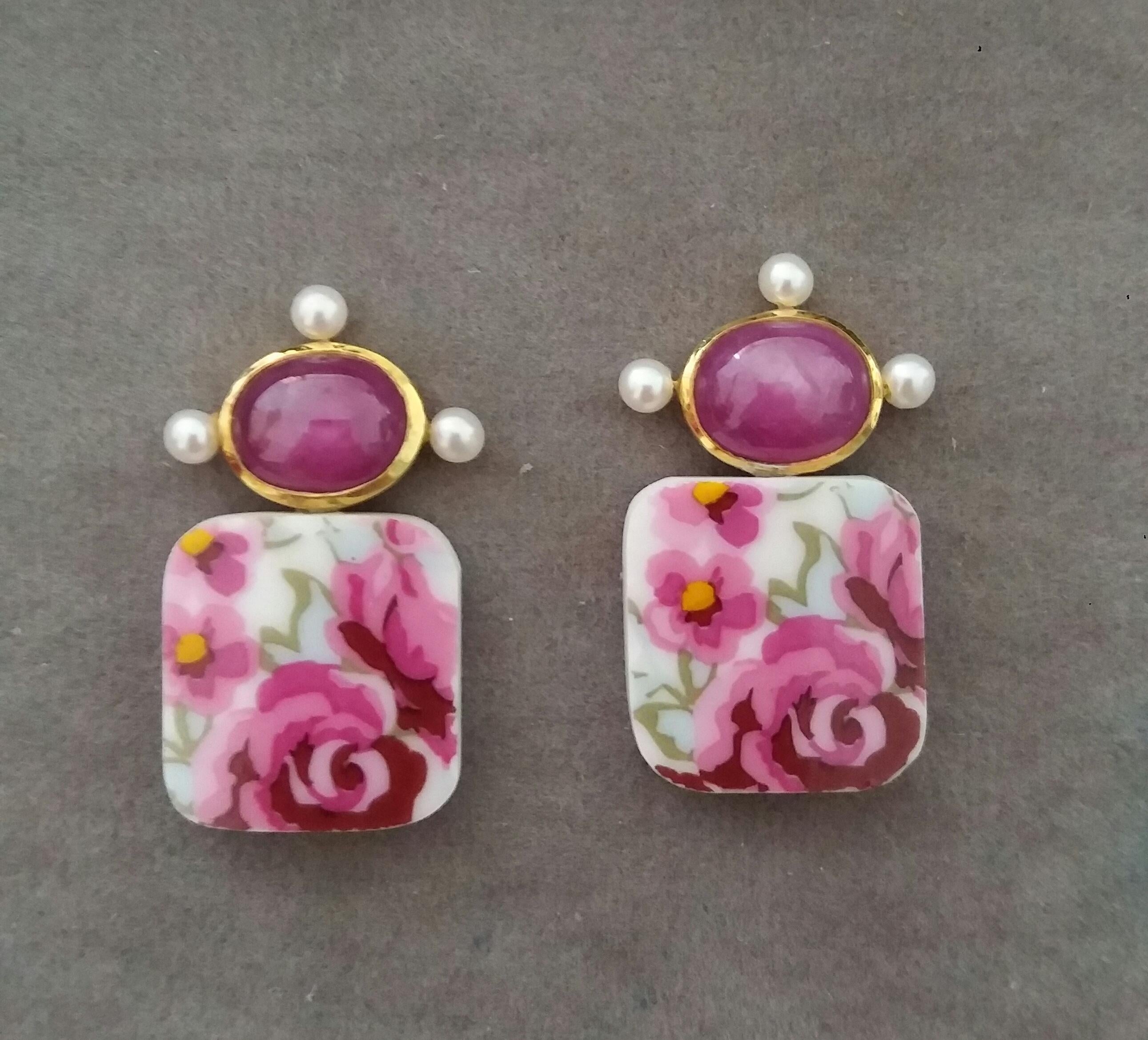 In these simple and chic earrings we have 2 Cushion Shape Ceramic measuring 16 x 17 mm.,suspended from 2 nice Natural Ruby oval cabochons size 8 x 10 mm  set in a 14 kt yellow gold bezel,with 3 small round fresh water pearls of 3 mm in diameter.

In