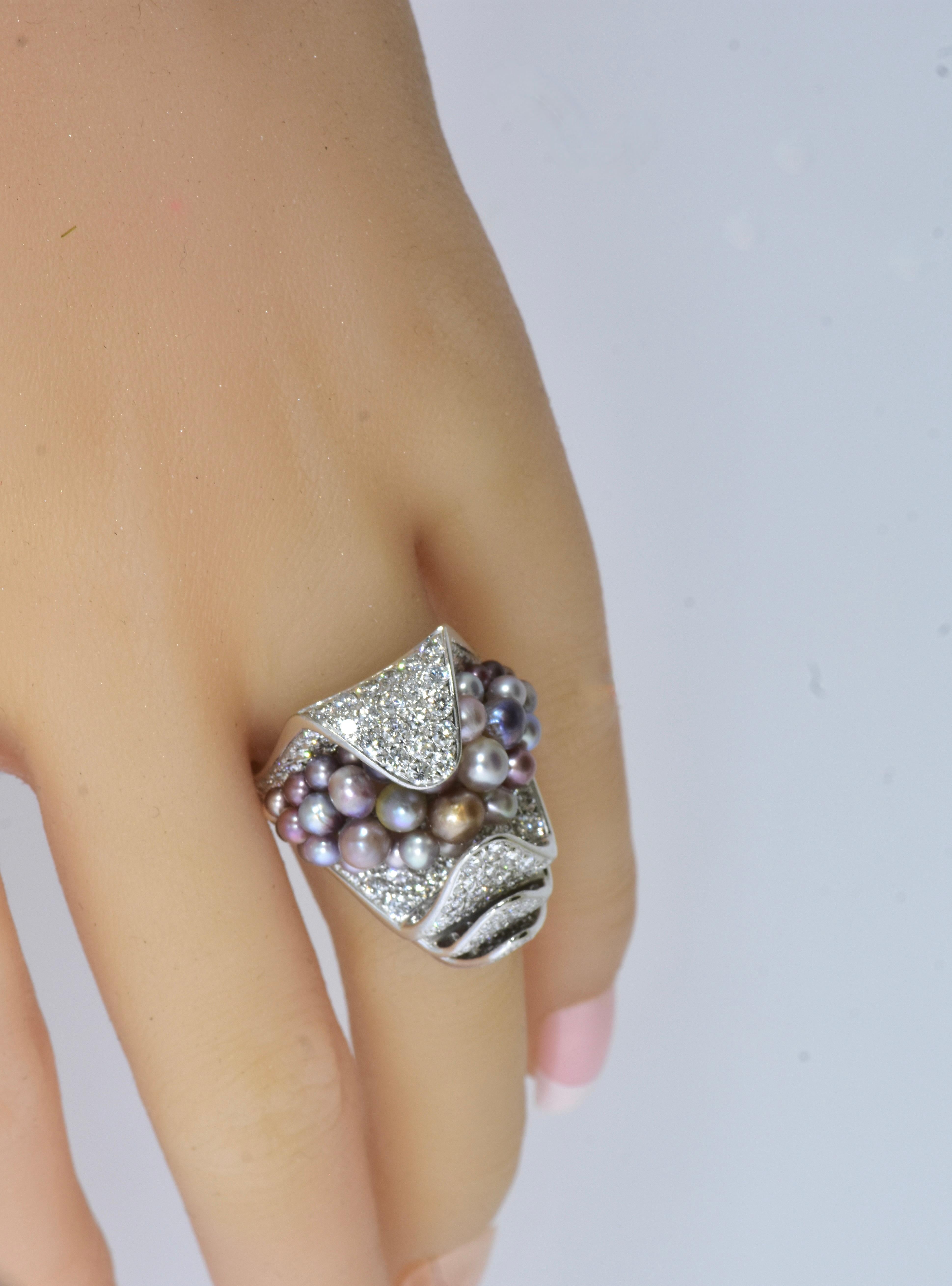 Anello modernista insolito di colore naturale, perle naturali e diamanti, circa 2000, con marchi francesi.

Incastonato in oro bianco 18 carati, questo grande anello ben lavorato a mano sembra aprirsi gradualmente.  per rivelare i suoi tesori di 
