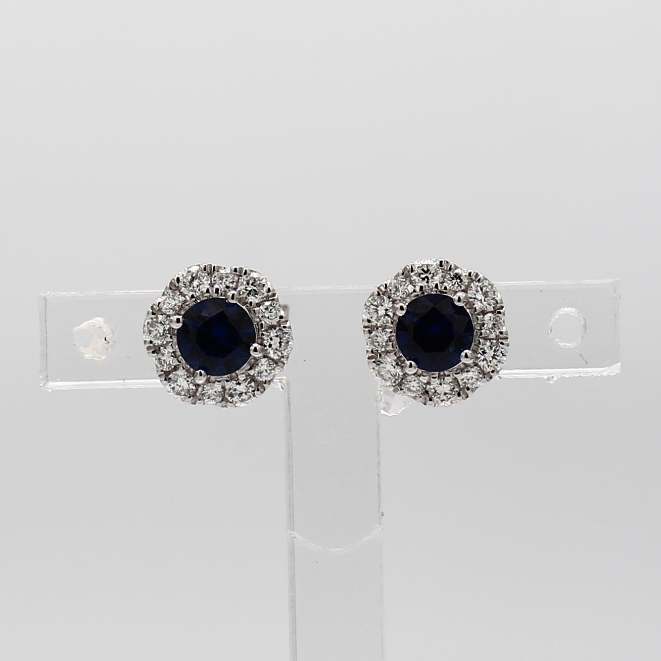 RareGemWorld's classic sapphire earrings. Mounted in a beautiful 14K White Gold setting with natural round cut blue sapphires. The sapphires are surrounded by natural round white diamond melee in a beautiful single halo. These earrings are