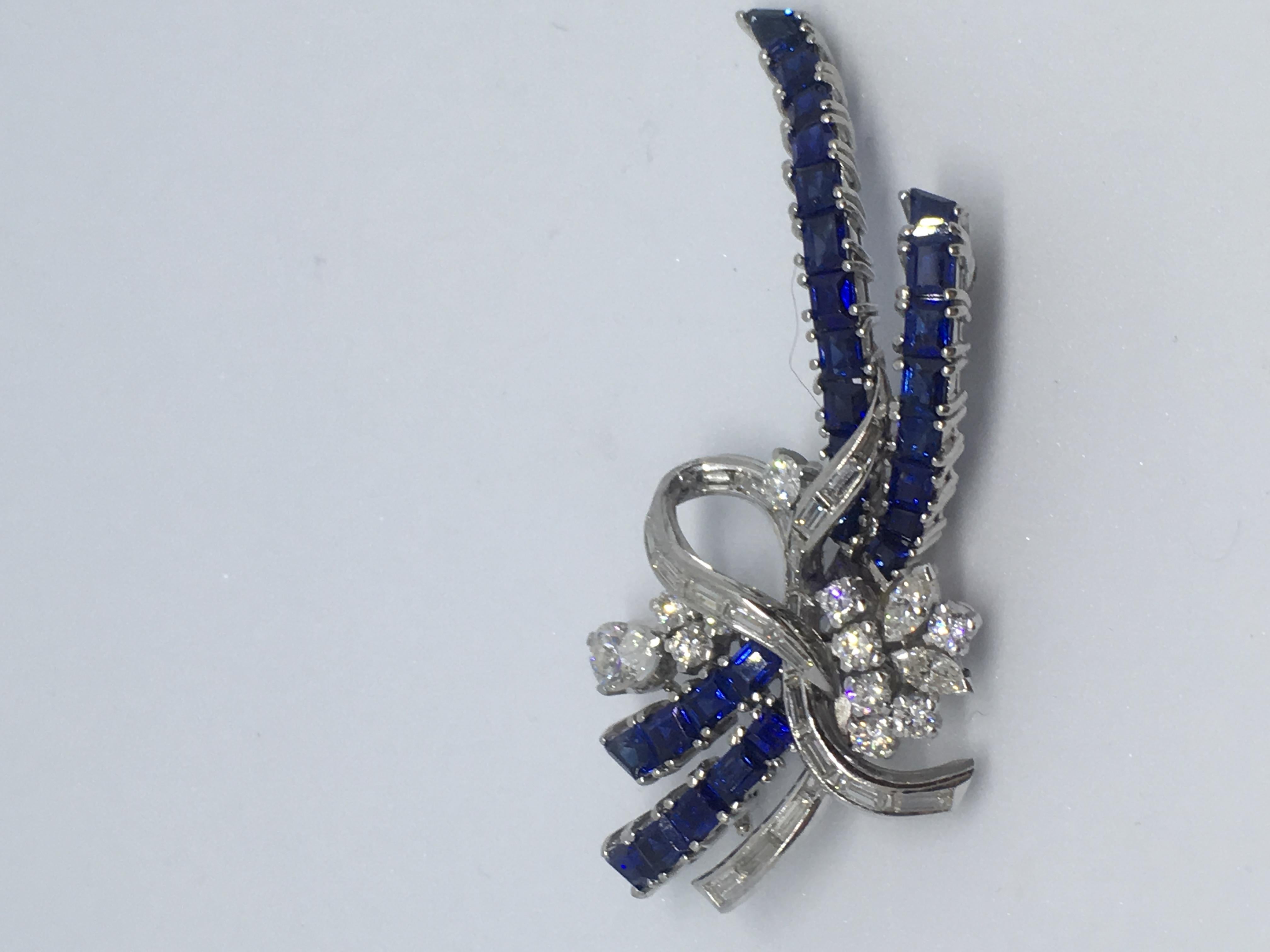 Brooch an abstract ribbon loop set with diamonds and sapphires. The diamond content of the brooch comprises 1 pear-shaped diamond 0.37ct 10 brilliant-cut diamonds .0.07 to0.03ct 2 marquises cut diamonds 0.07ct each. There are 20 baguette-cut