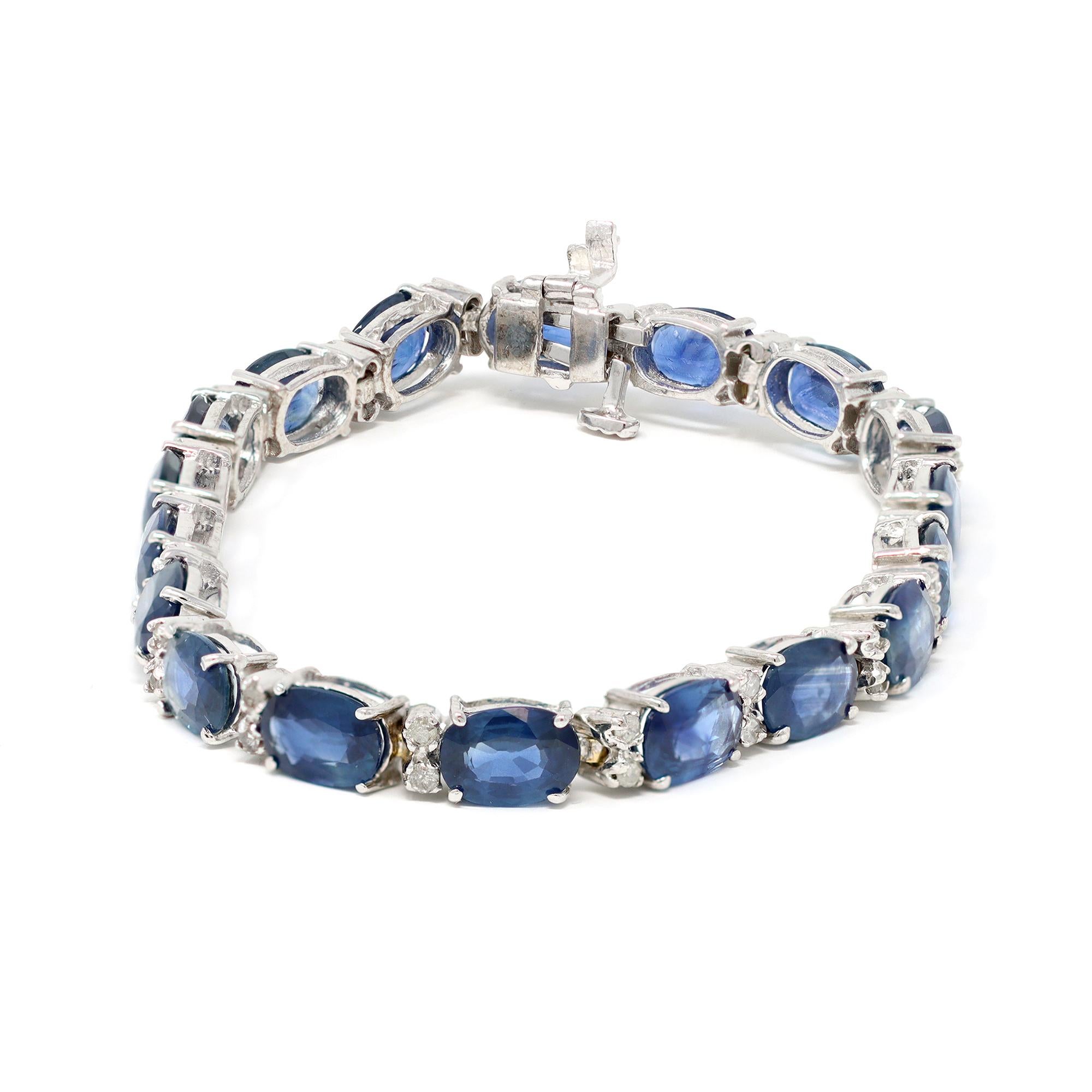 A tennis style bracelet featuring a line of calibrated blue sapphires alternated with accent diamonds. The sapphires are oval shape and well matched in color, displaying a medium deep blue. The estimated weight of the sapphires is 9 carats. The