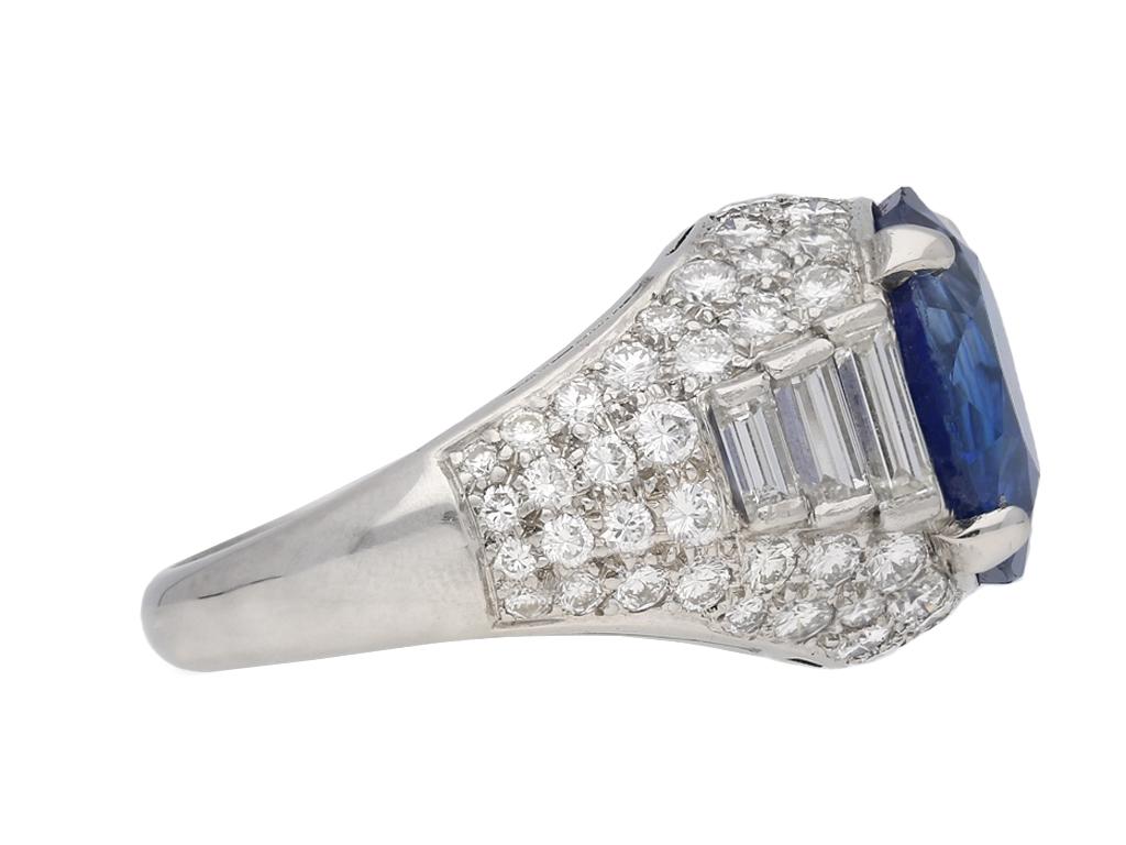 Vintage sapphire and diamond cluster ring by Oscar Heyman Brothers. Set with a cushion shape old cut natural unenhanced Ceylon sapphire in an open back claw setting with an approximate weight of 11.45 carats, flanked by six rectangular channel set