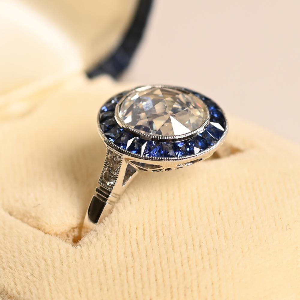 Questo squisito anello di fidanzamento mette in mostra un affascinante diamante con taglio a rosa al centro, incastonato a castone per evidenziare il suo fascino vintage. La pietra centrale, del peso di circa 1,50 carati, è di colore K e di purezza